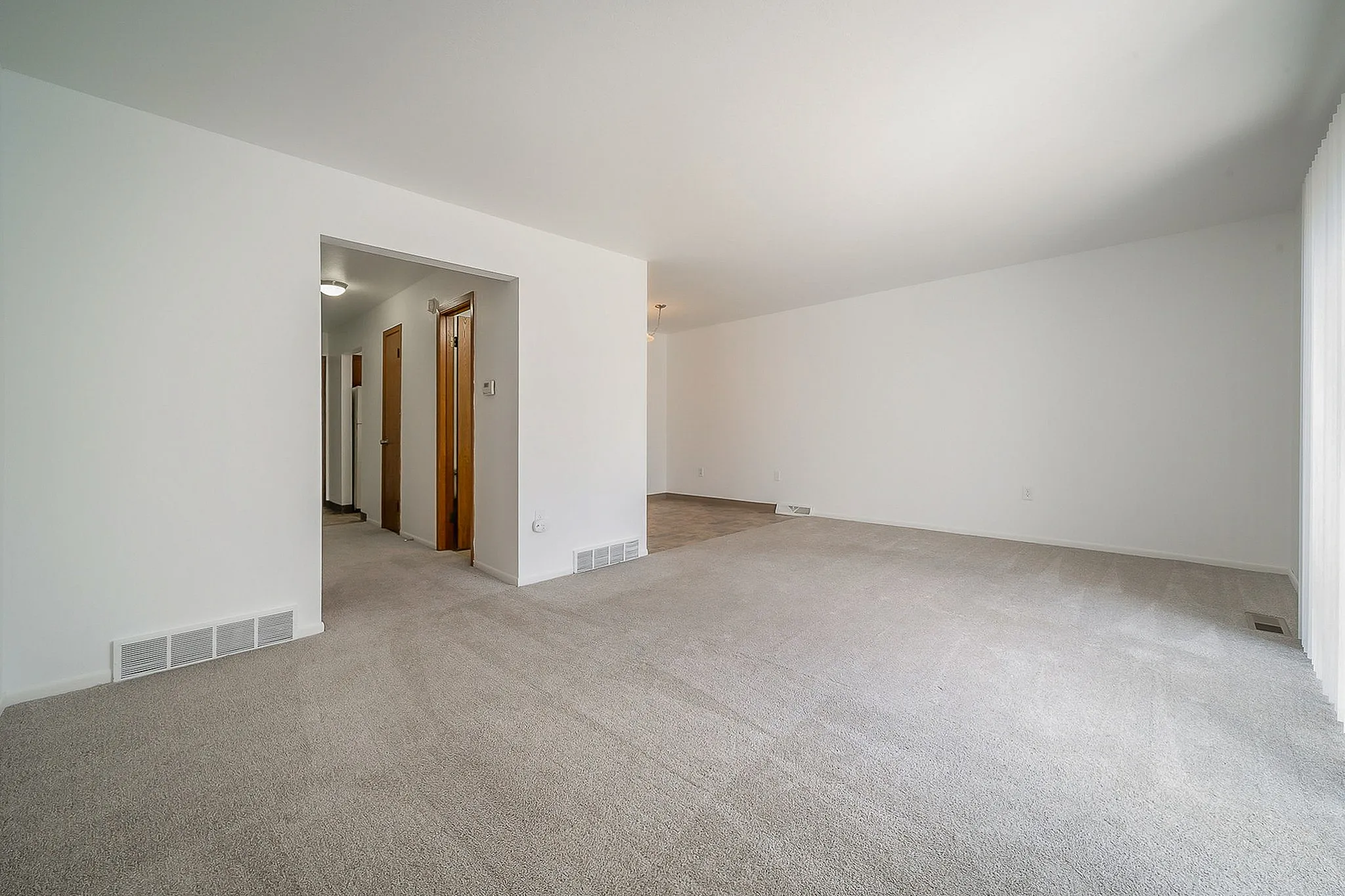 Spacious and bright living area with plush carpeting and open layout, perfect for comfortable modern living.