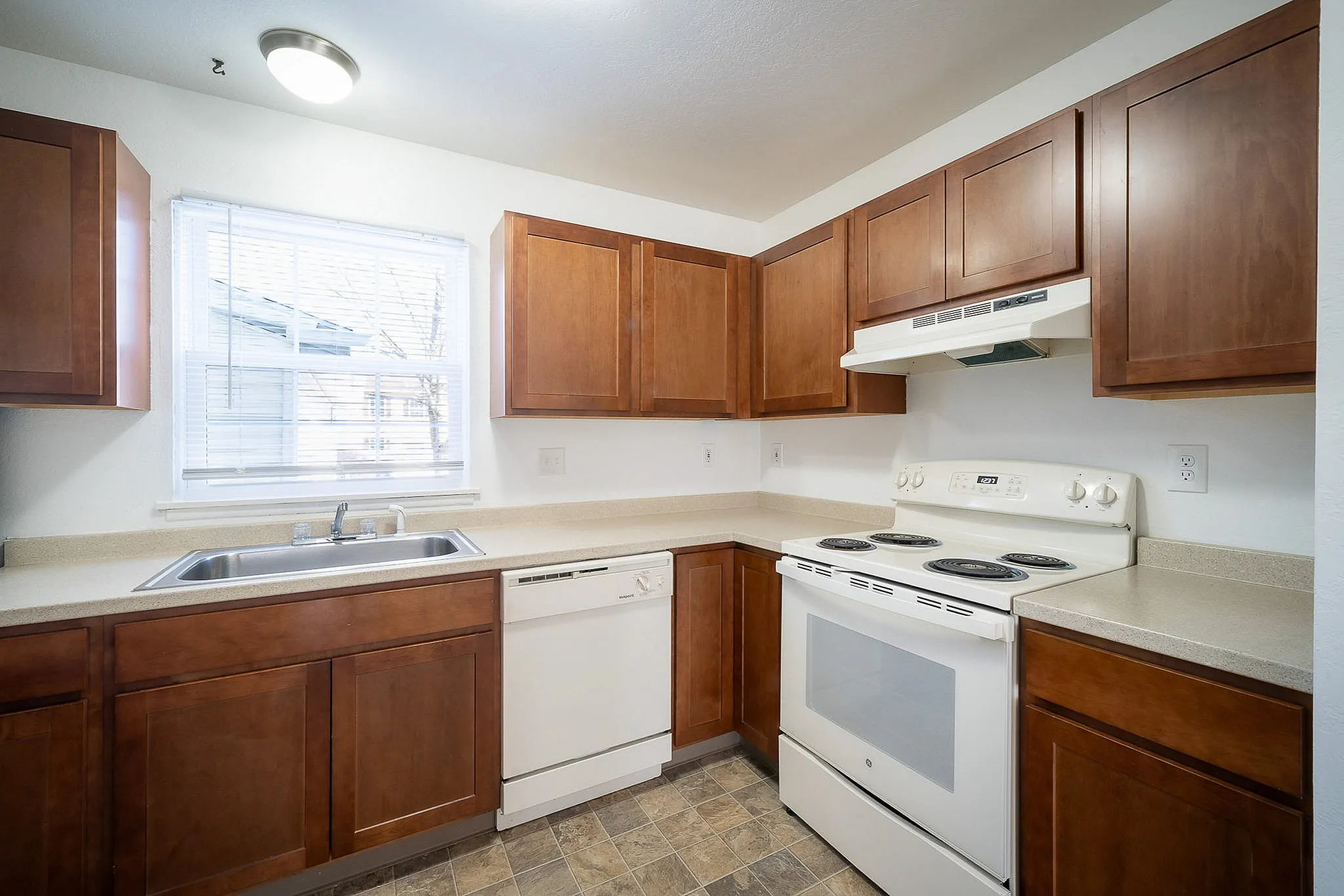 Charming kitchen with modern appliances, rich wood cabinetry, and ample natural light from a large window, perfect for culinary enthusiasts.