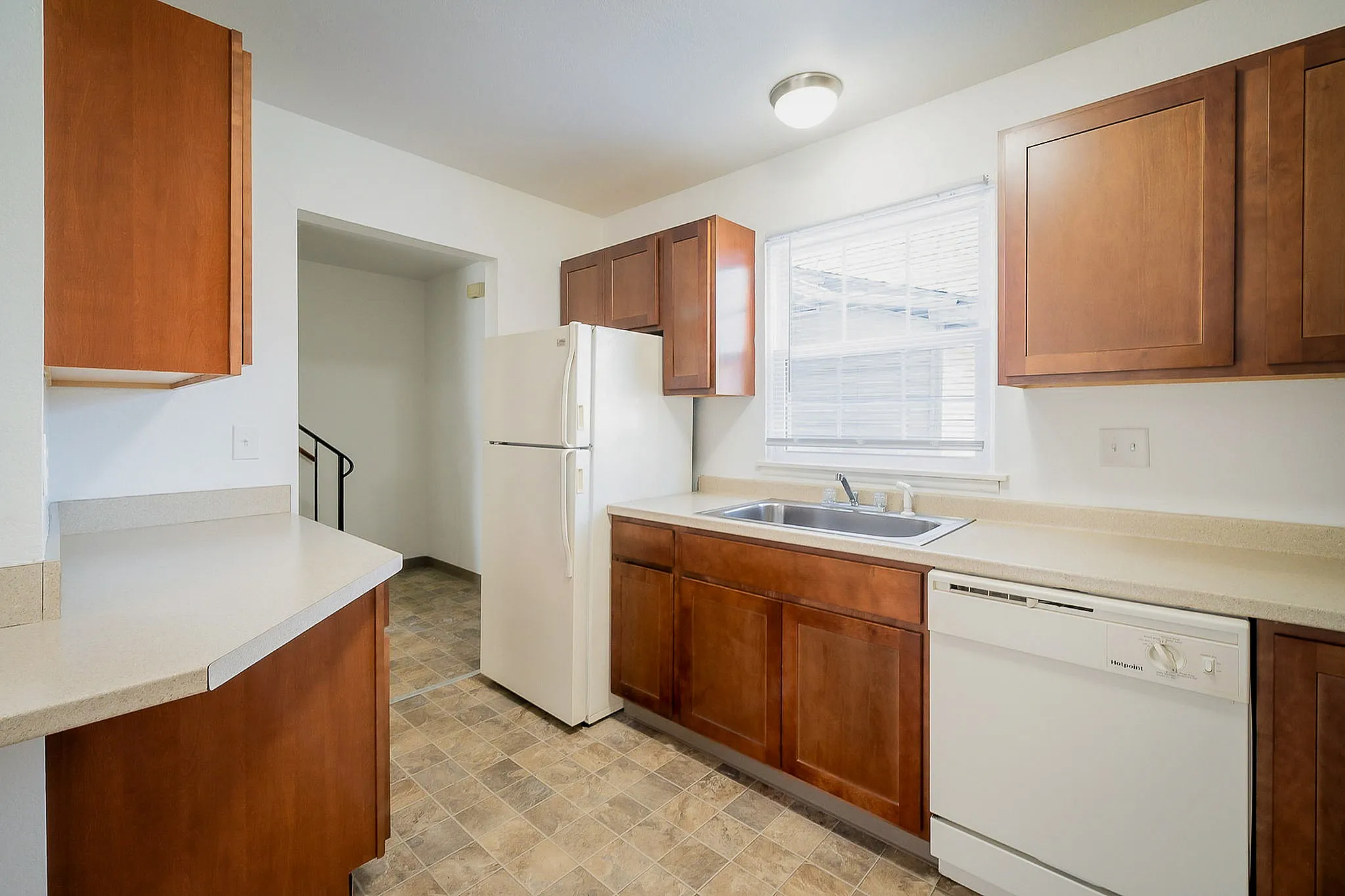Bright and modern kitchen with sleek countertops, wood cabinets, and ample natural light, perfect for culinary delights.