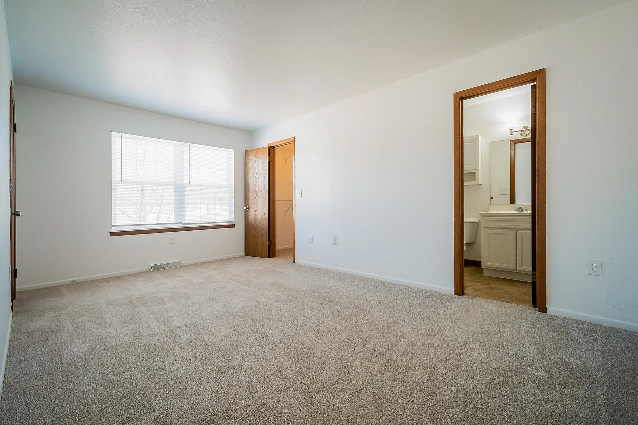 Bright and spacious bedroom with large window and en-suite bathroom, perfect for comfort and relaxation.