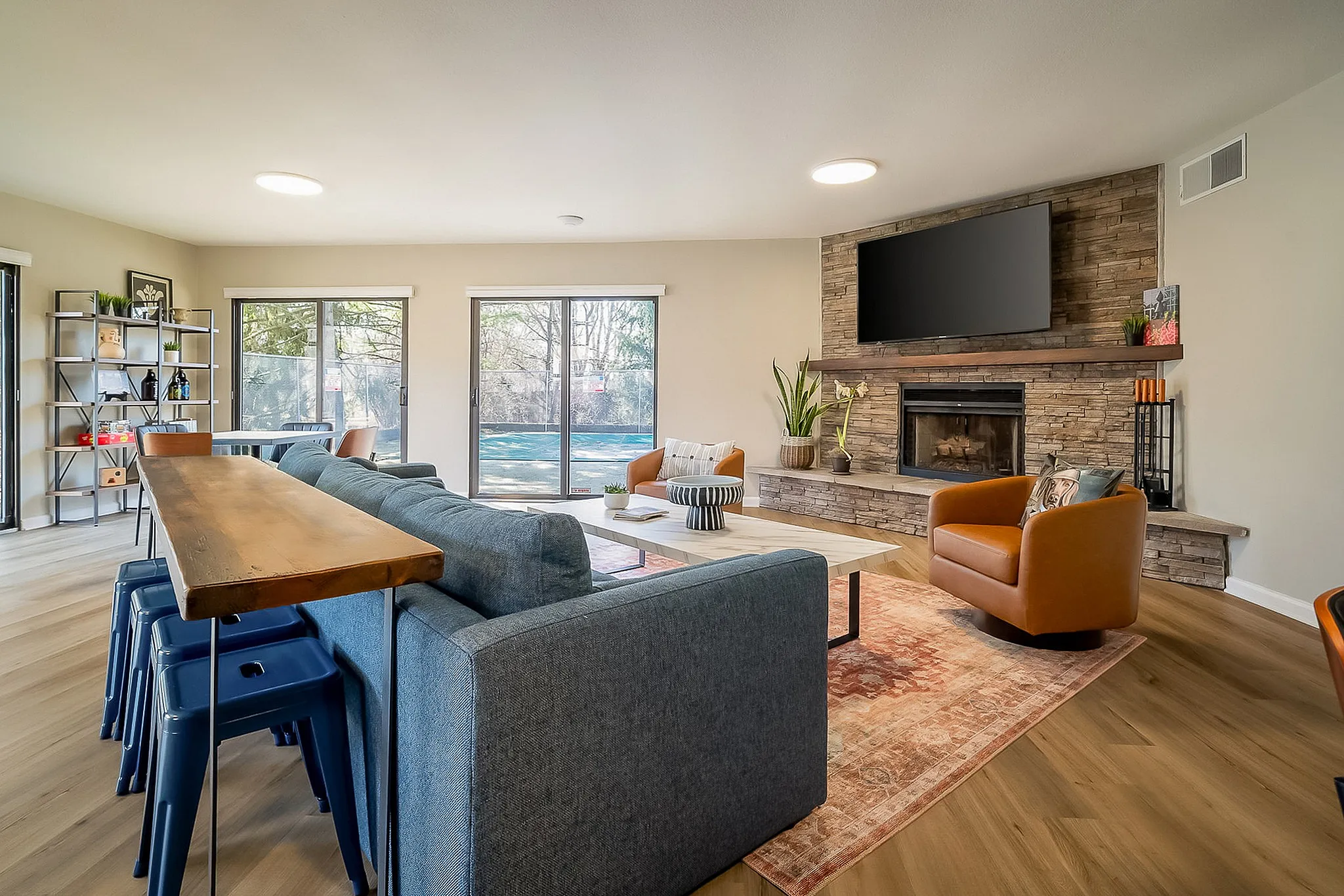 Bright and modern living room with large windows, a cozy fireplace, and stylish furniture, ideal for relaxing and entertaining.
