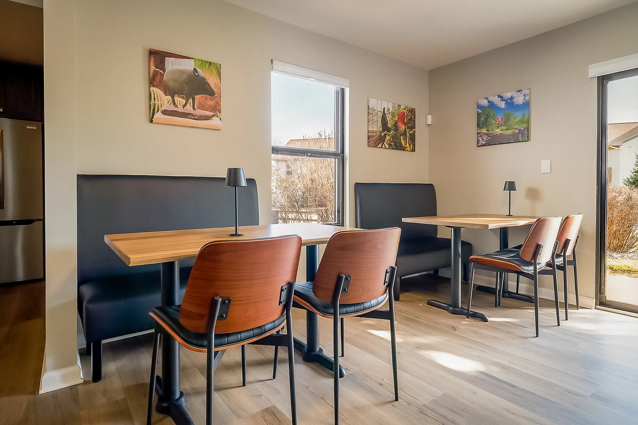 Bright dining area with modern wooden tables, elegant black seating, and scenic window views, creating an inviting atmosphere.