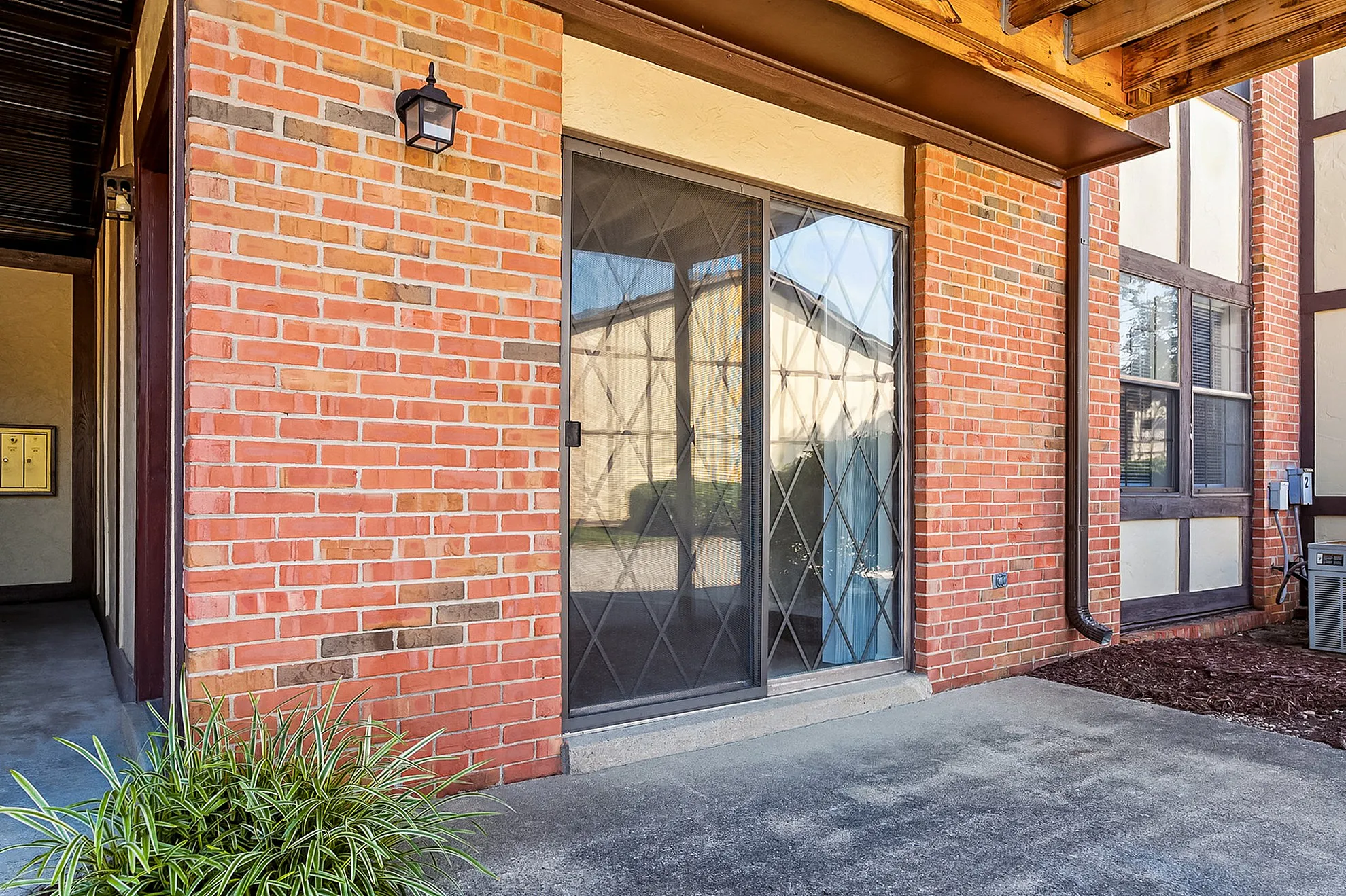 Inviting apartment entrance with elegant glass sliding doors and charming brick walls, offering a warm and welcoming exterior.