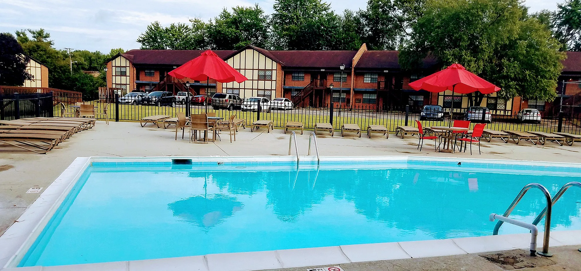 Inviting outdoor pool area with vibrant red umbrellas and comfortable lounge chairs, perfect for relaxation and enjoyment.