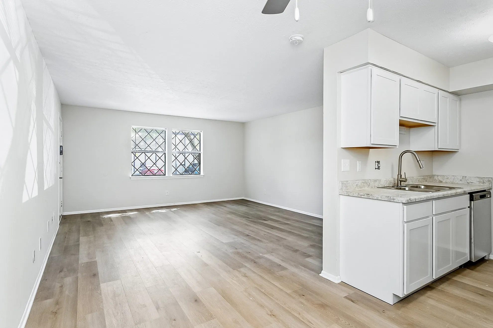 Bright and airy apartment with polished wood floors and large windows, featuring a modern kitchen with sleek cabinetry and stainless steel sink.