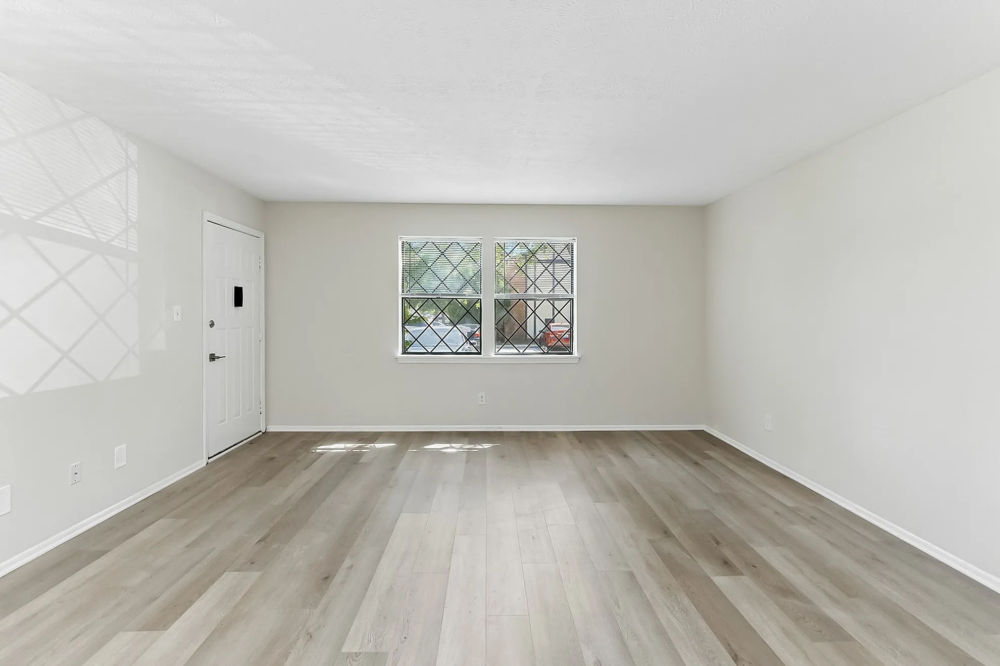 Bright, open living space with stylish hardwood flooring and large windows, offering abundant natural light.