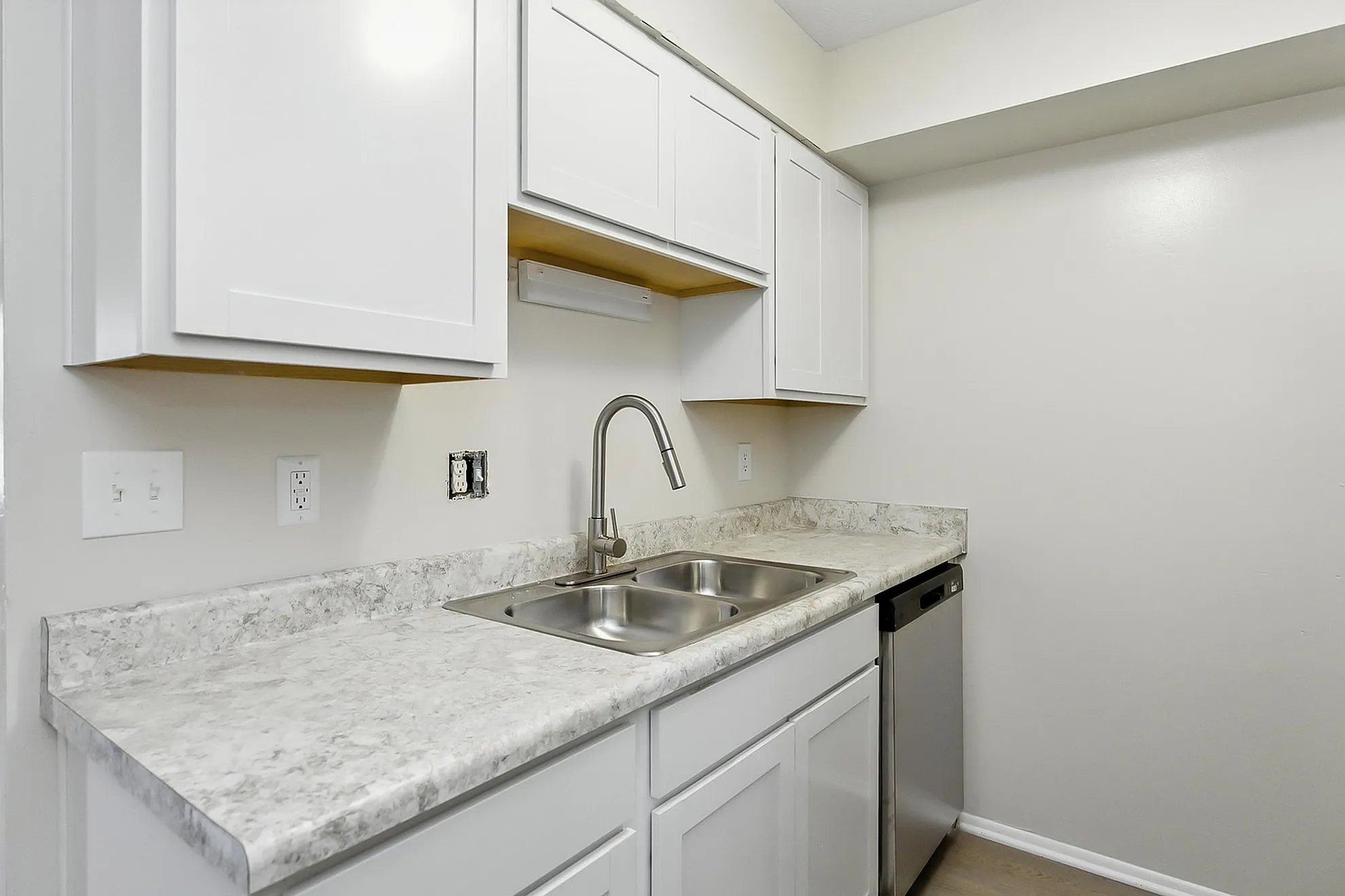 Modern kitchen with sleek white cabinetry, elegant marble countertops, and stainless steel dishwasher.