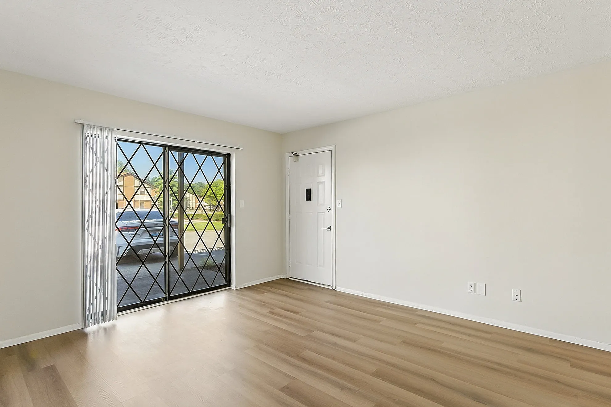Bright and airy room with elegant hardwood flooring, large sliding glass doors, and charming entryway.