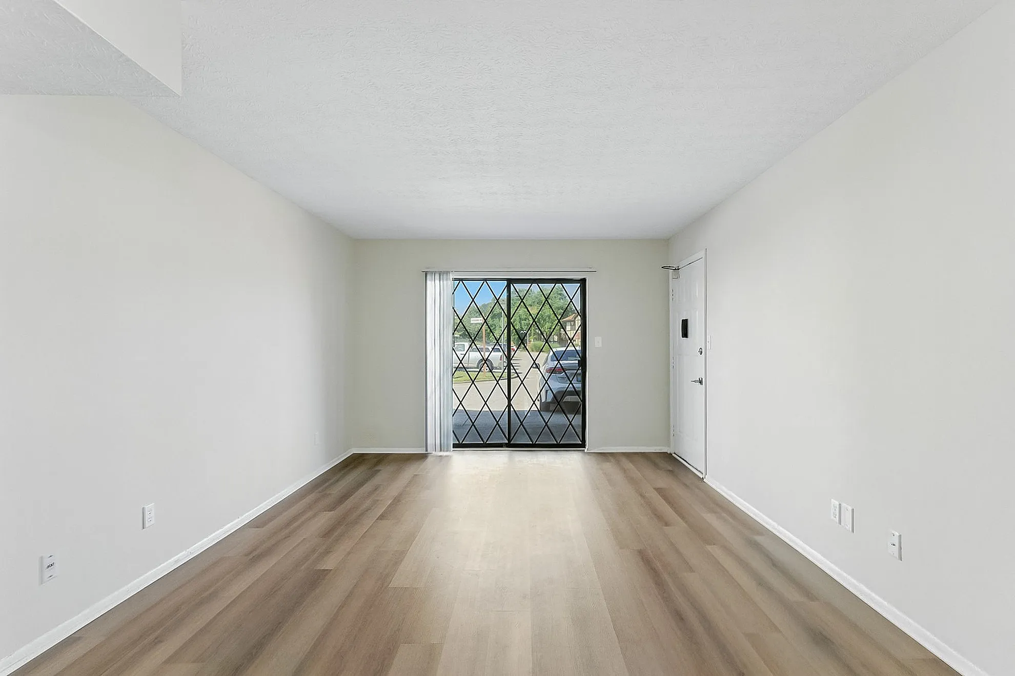 Bright and spacious living room with elegant wooden flooring and large windows providing ample natural light.