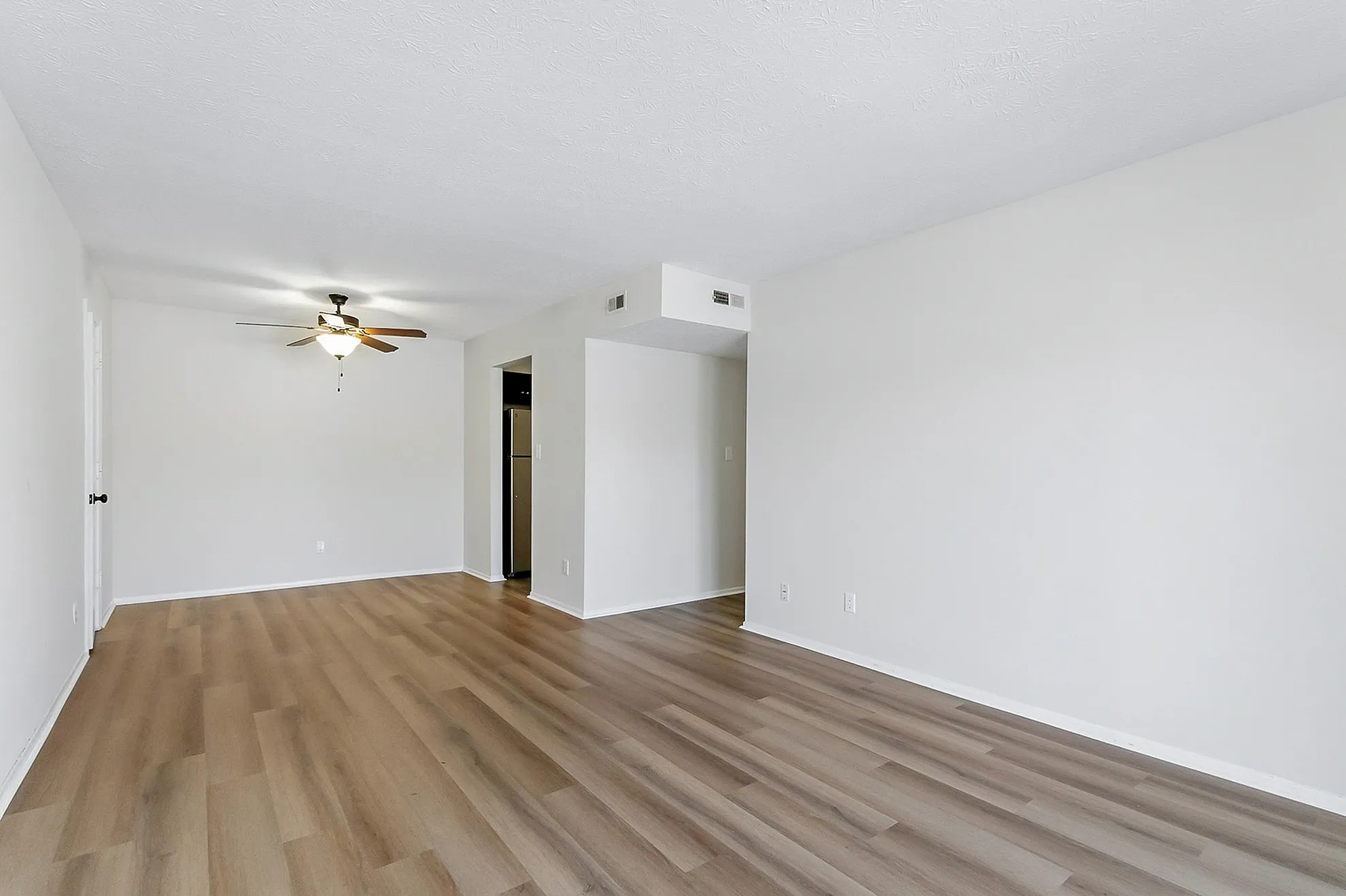 Bright and spacious living room with modern hardwood flooring and elegant ceiling fan, perfect for stylish living.
