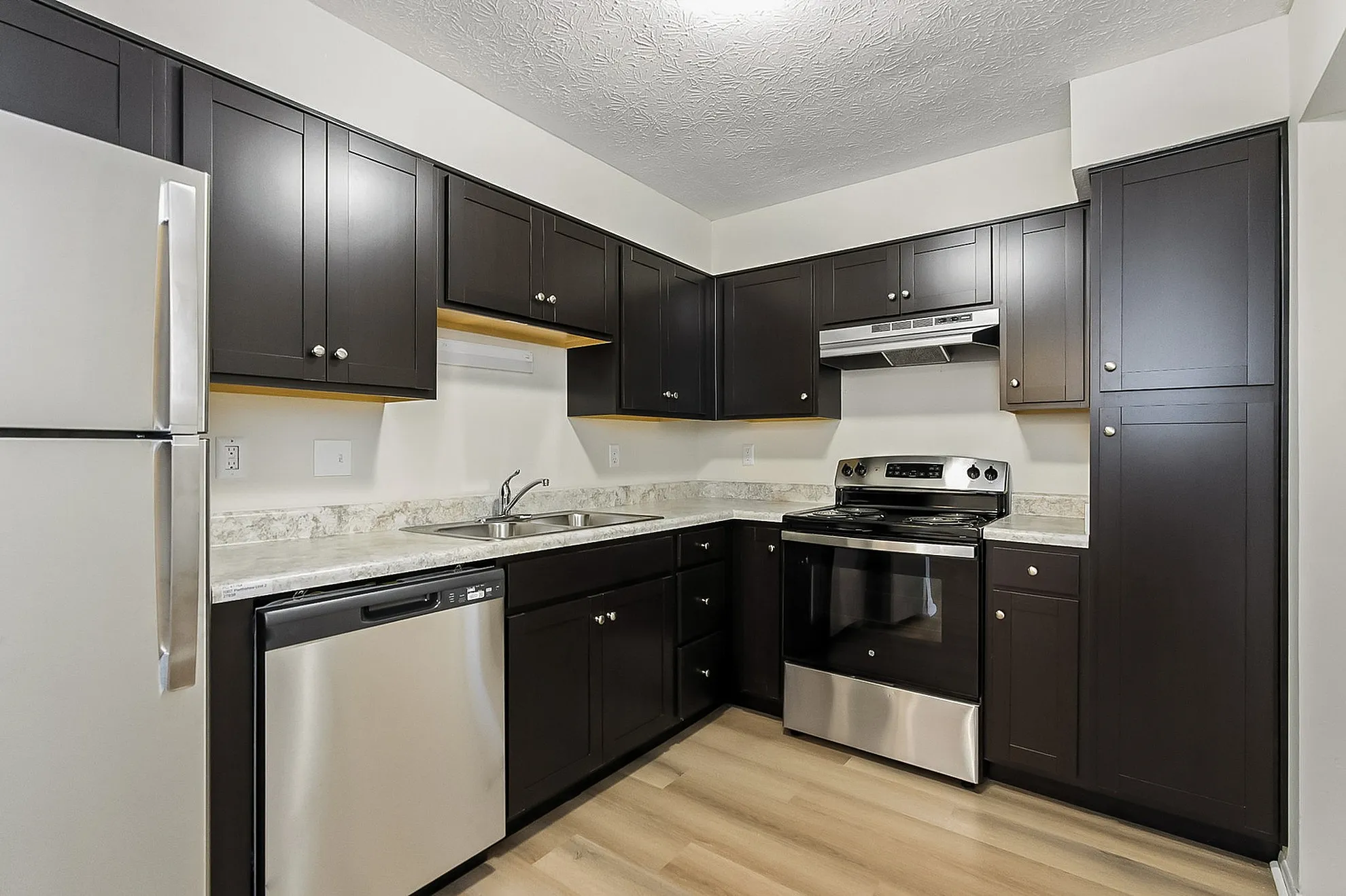 Modern kitchen with sleek dark cabinetry, stainless steel appliances, and elegant countertops.