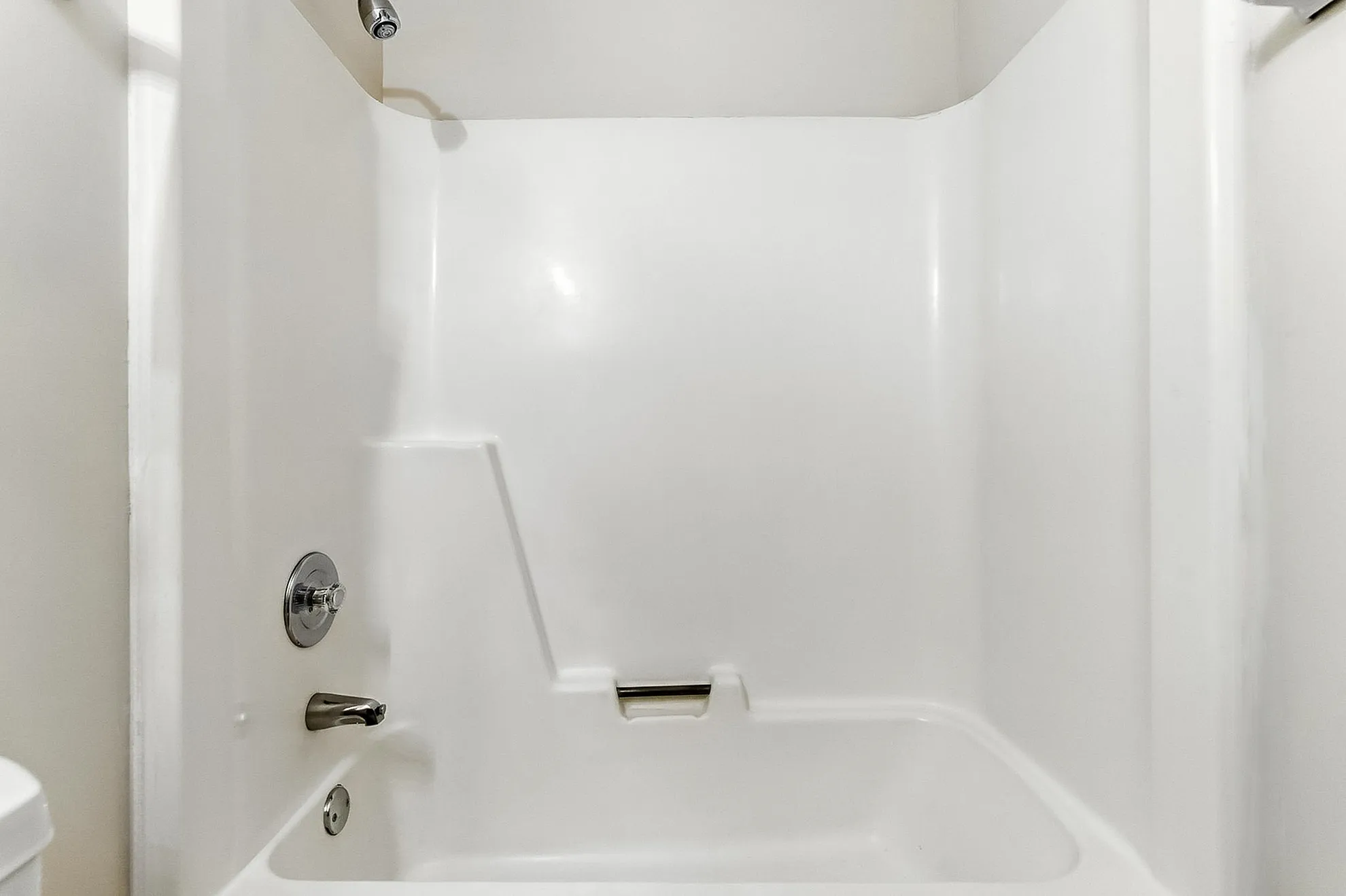 Modern white bathtub with sleek chrome fixtures in a bright, pristine bathroom space.