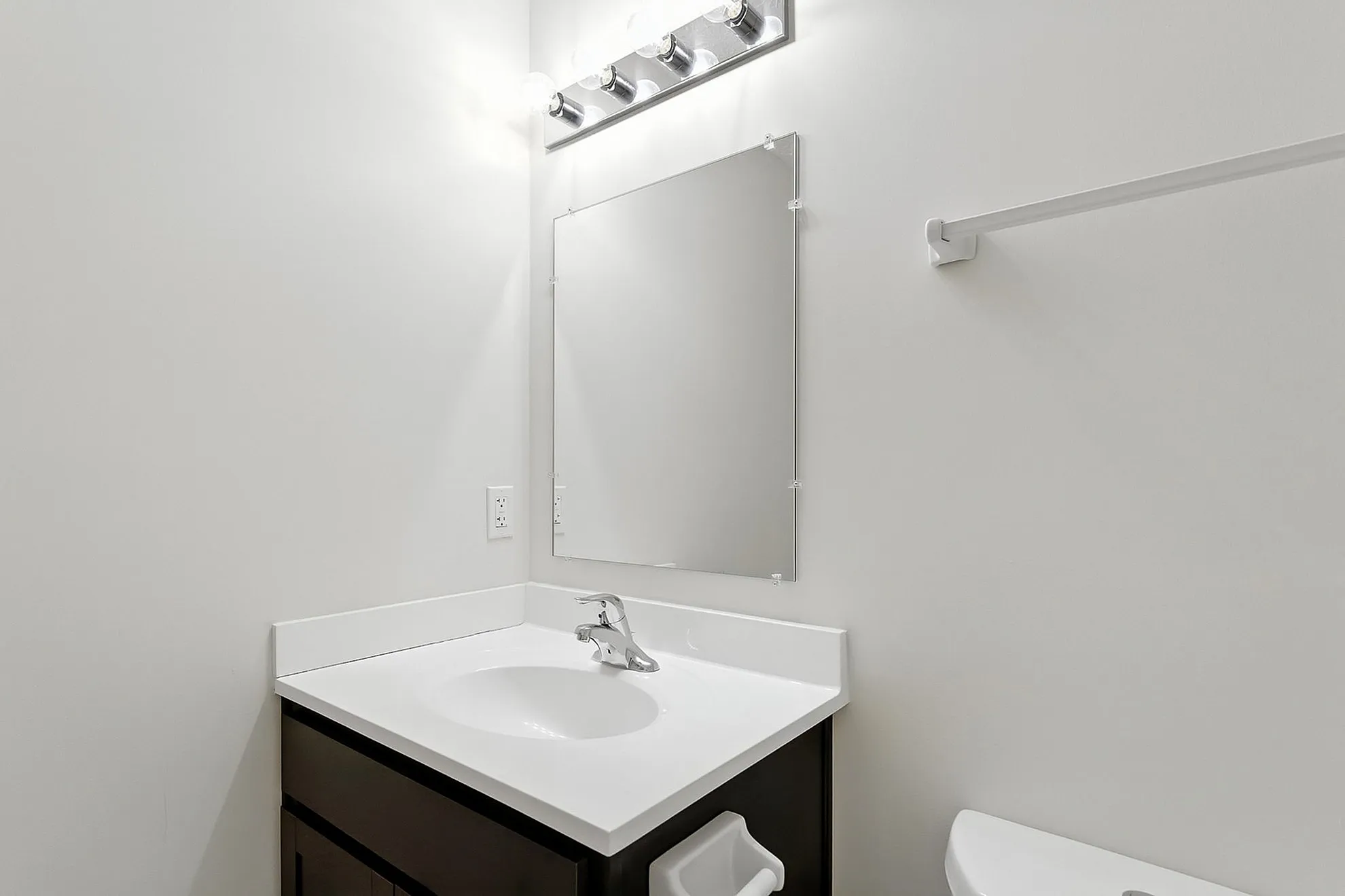 Bright and modern bathroom with sleek white countertop, elegant fixtures, and ample lighting.