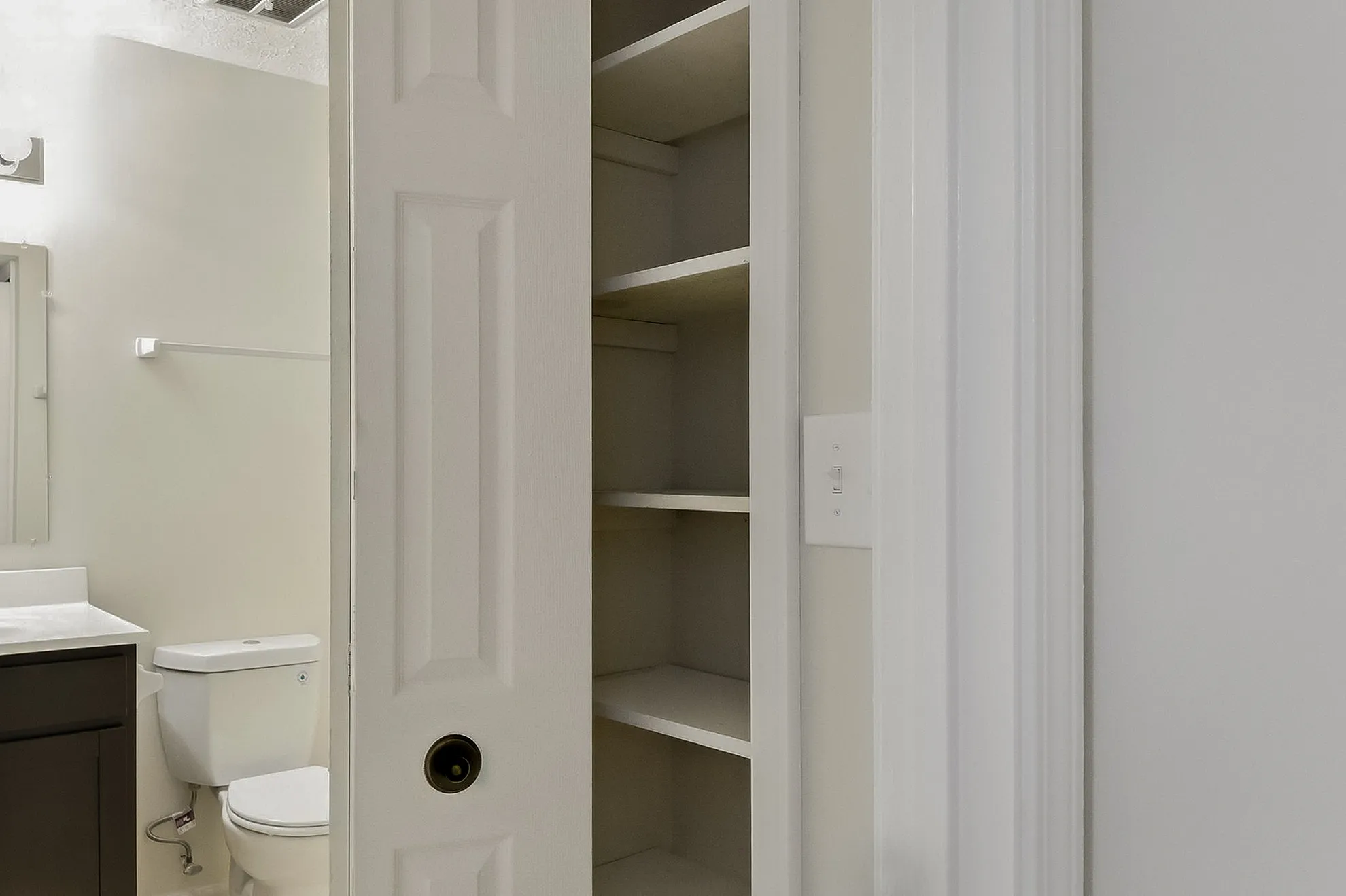 Modern bathroom featuring a sleek vanity, contemporary toilet, and convenient built-in shelving.