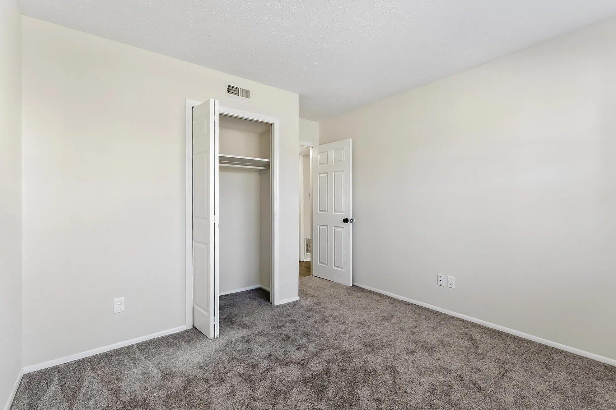 Bright and inviting bedroom with plush carpeting and a spacious closet, perfect for personalizing your dream space.
