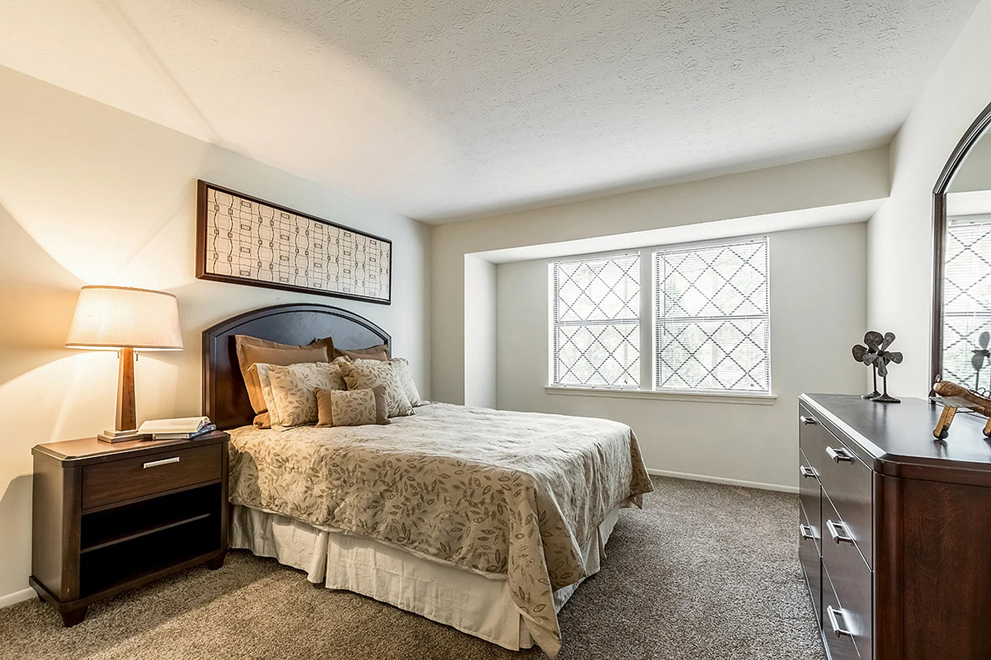 Inviting cozy bedroom featuring a plush bed with elegant floral bedding, ambient lighting, and a large window offering natural light.