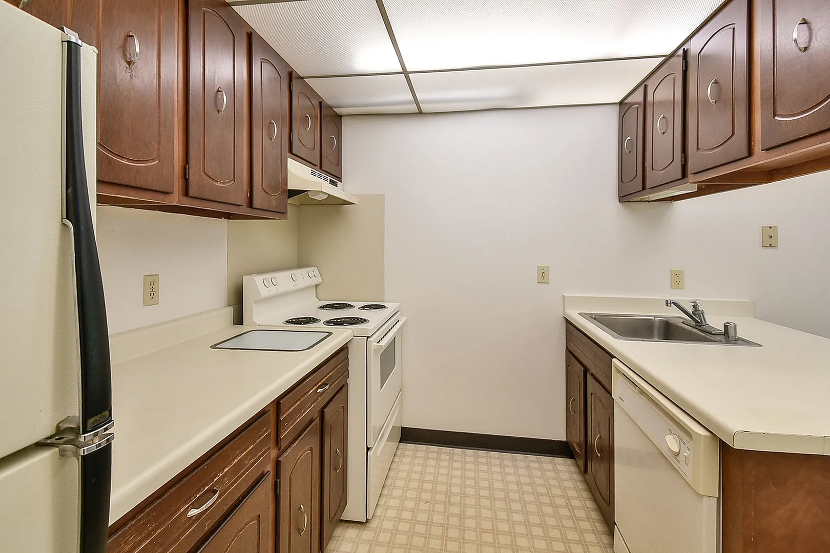 Charming apartment kitchen with warm wooden cabinets, spacious countertops, and classic appliances creating a cozy cooking space.
