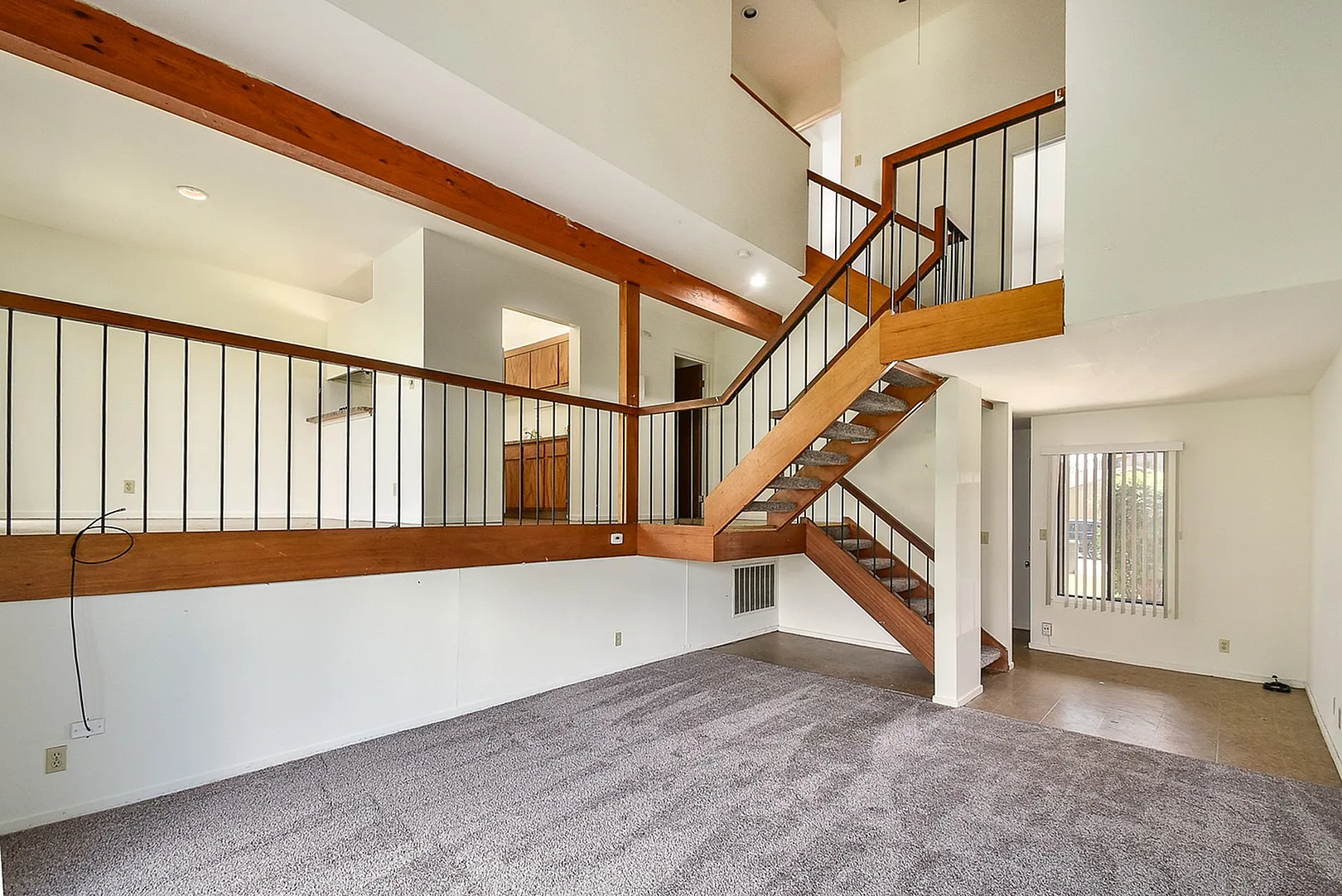 Modern duplex interior showcasing elegant wooden stairs, open railing, and abundant natural light through large windows.
