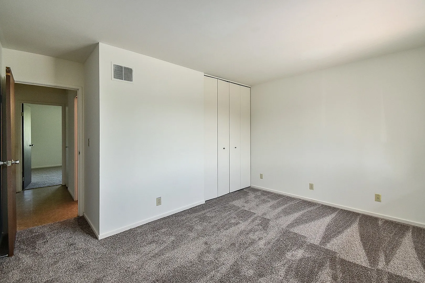 Bright and spacious bedroom with plush carpeting and elegant closet doors, perfect for creating your cozy retreat.