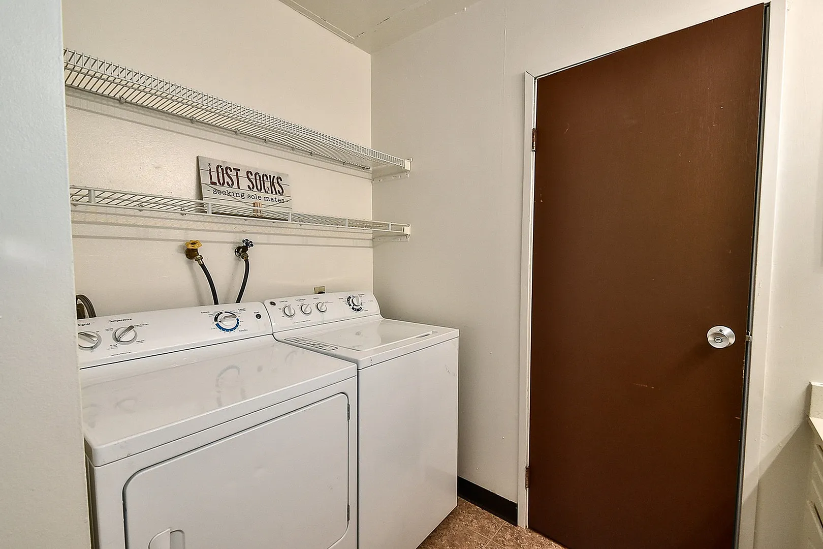 Charming laundry room with modern washer and dryer, efficient shelving, and a stylish touch for a cozy home.