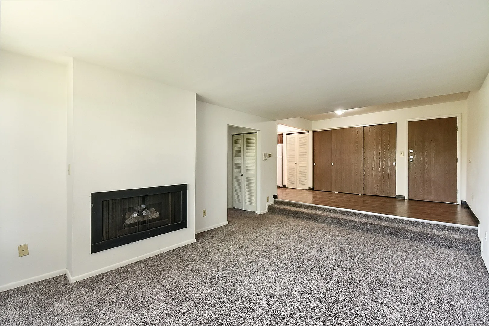 Inviting living area with cozy carpet, modern fireplace, and rich wooden finishes, perfect for relaxation and gatherings.