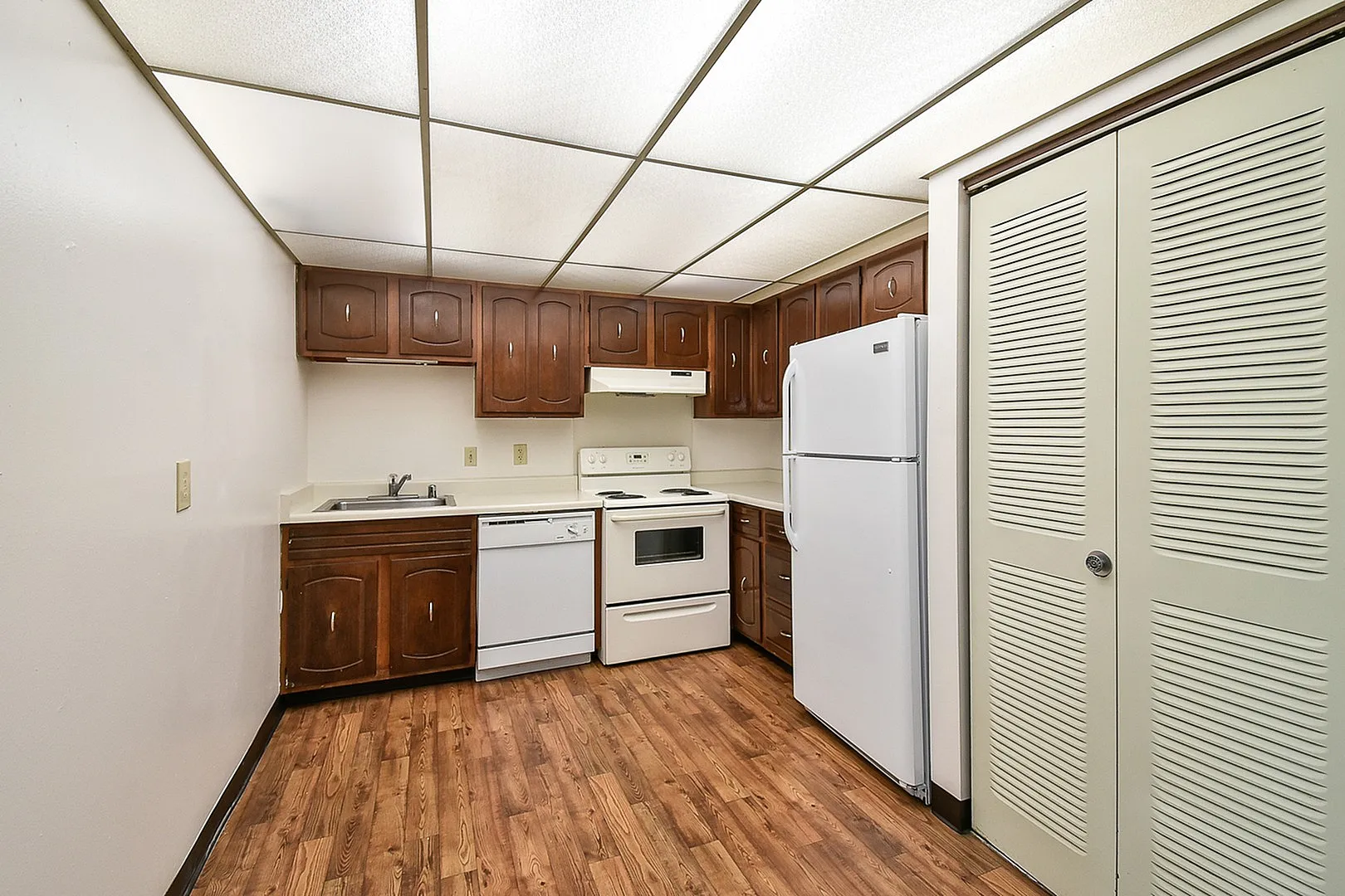 Charming kitchen with rich wooden cabinets, modern appliances, and elegant wood-style flooring.