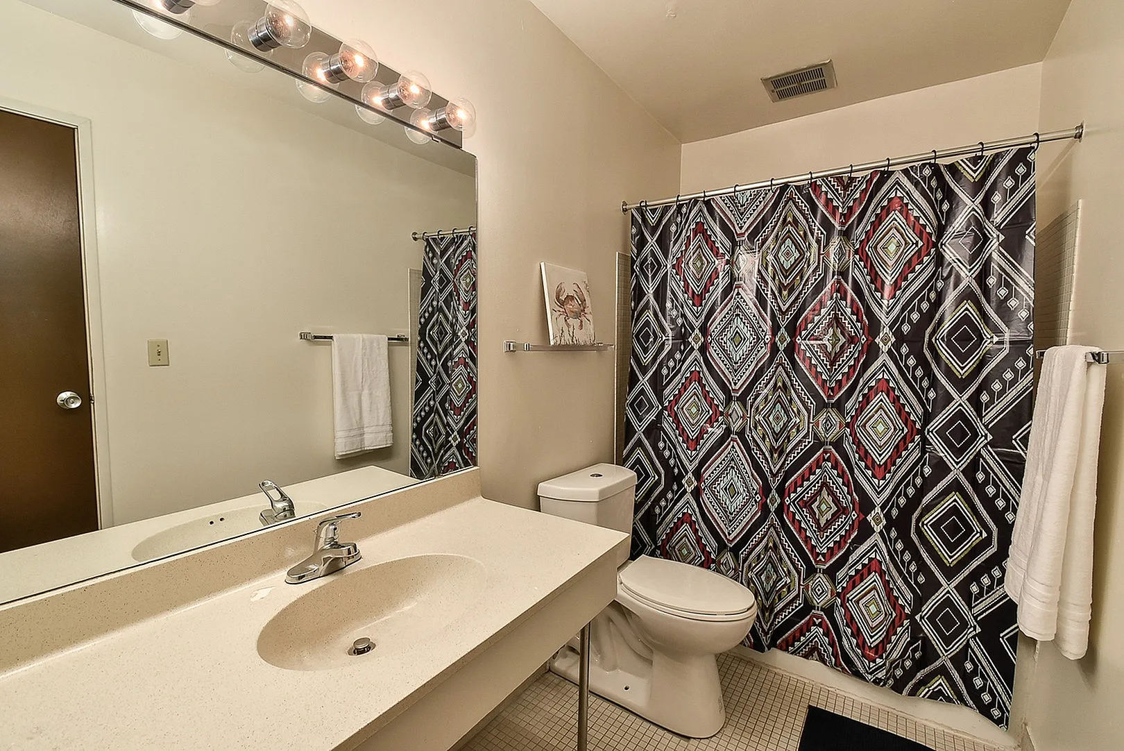 Modern bathroom featuring a sleek countertop, stylish geometric shower curtain, and elegant lighting fixtures.