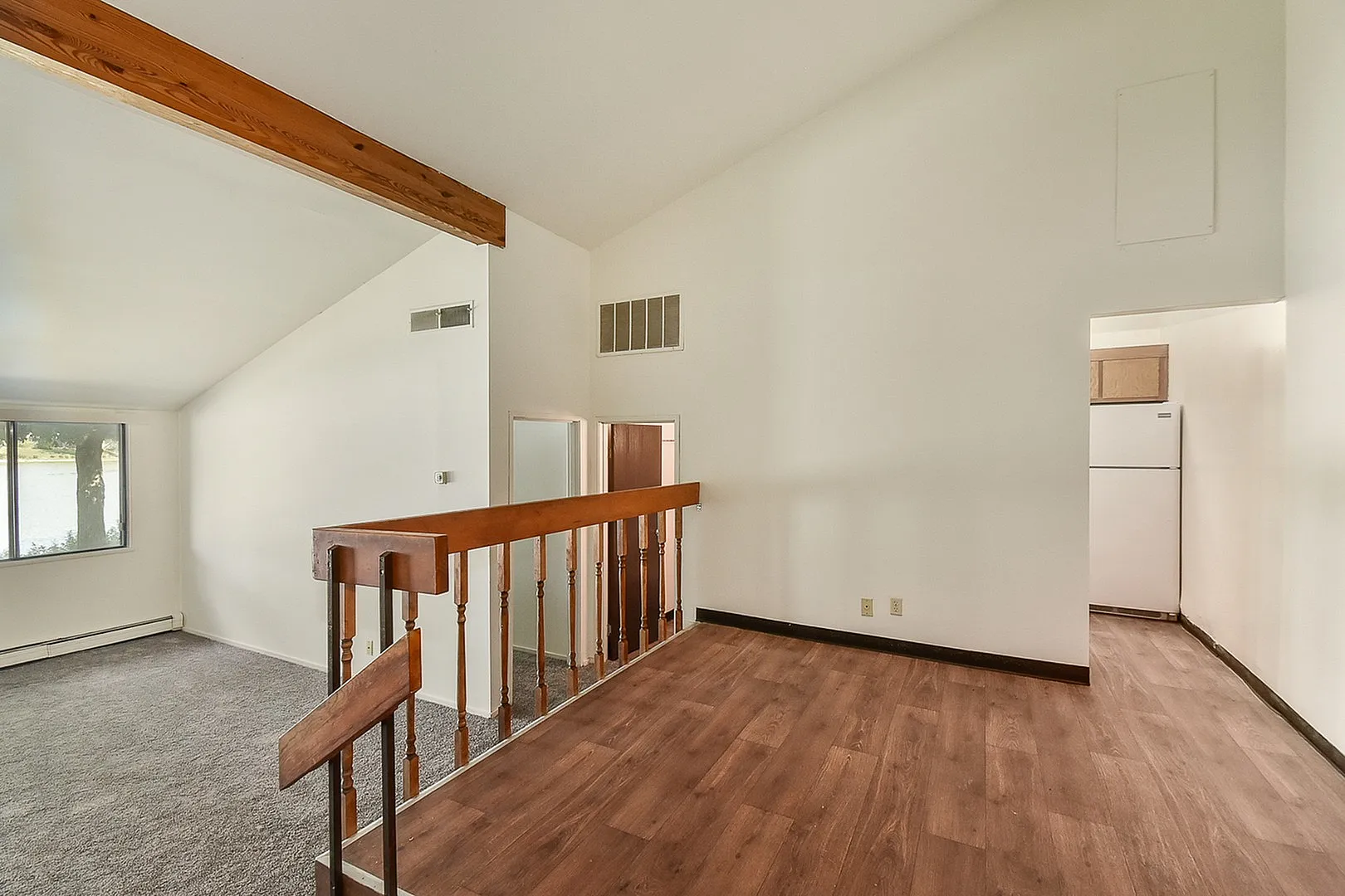 Inviting open-plan living area with elegant wooden beam accents and modern flooring, capturing serene natural light from the large window.