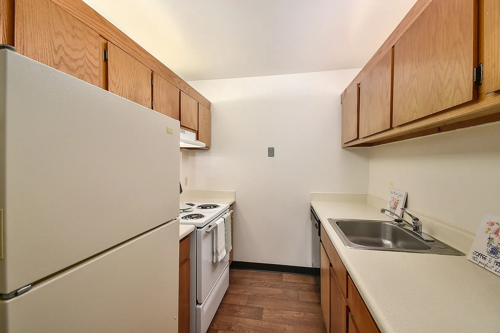 Charming galley kitchen with wooden cabinetry, sleek countertops, and modern appliances offering a cozy cooking space.