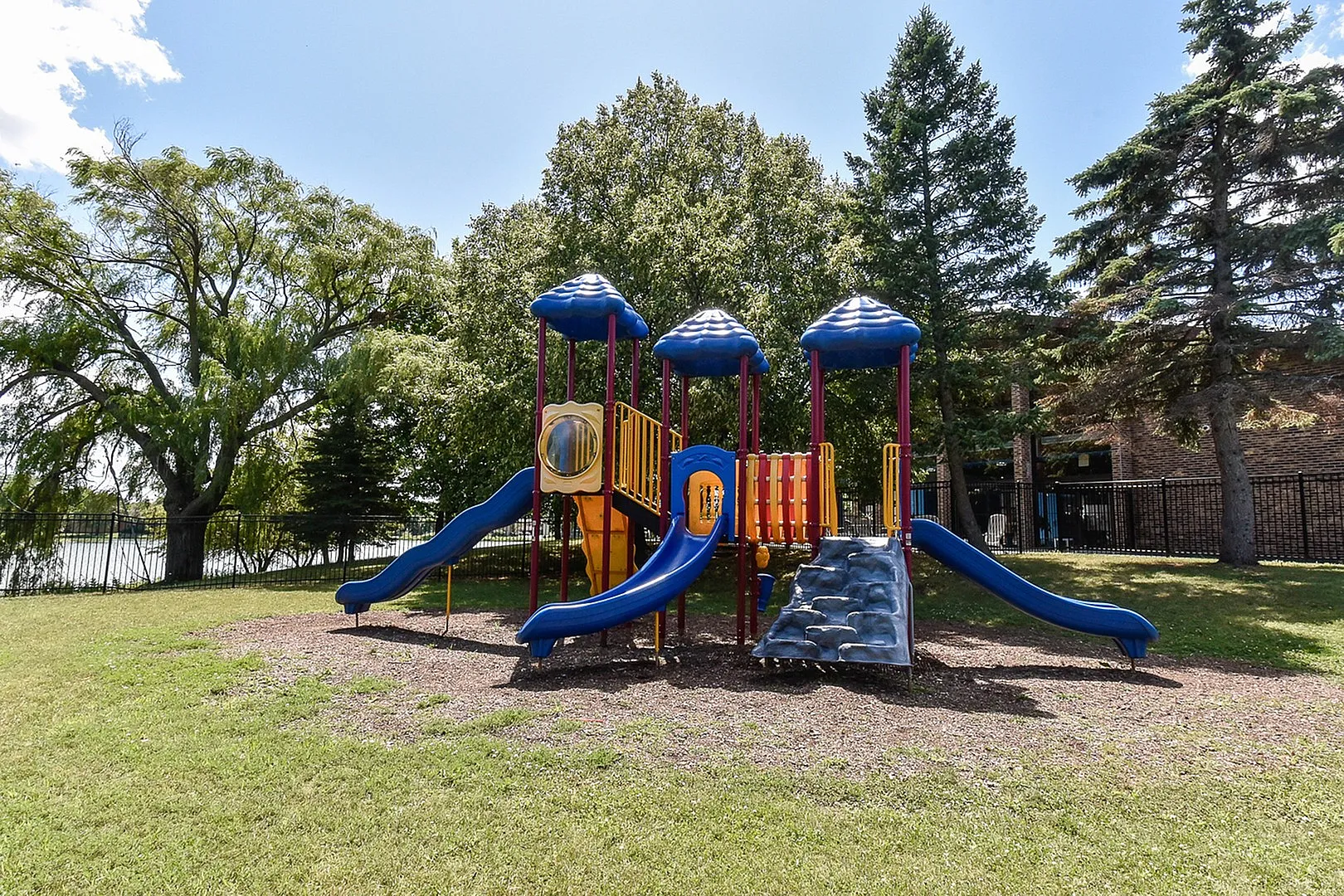 Charming outdoor playground featuring vibrant slides and climbing structures set amidst lush greenery, perfect for family living.