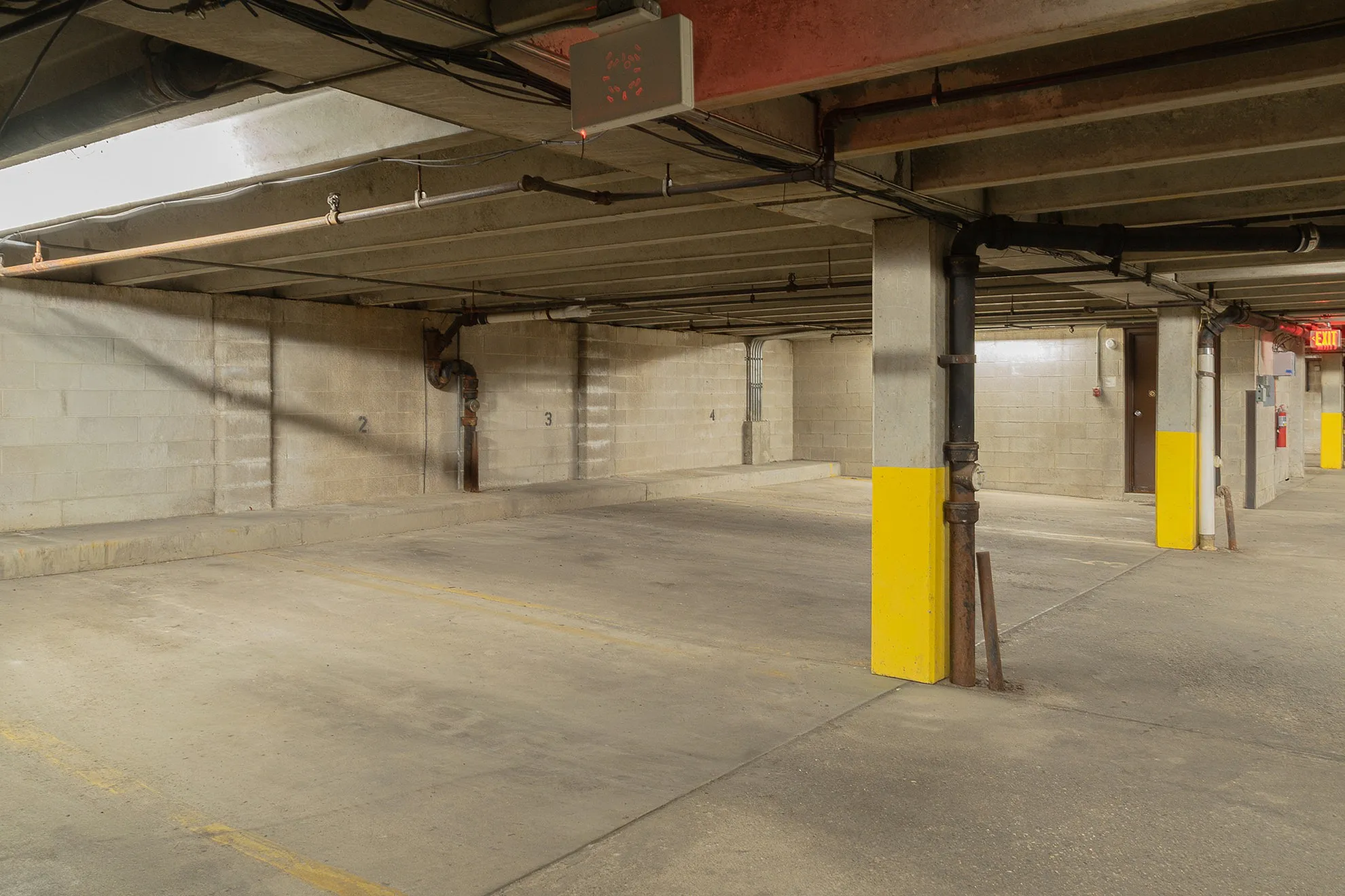 Secure and spacious underground parking garage with numbered spots and bright yellow safety pillars, ideal for urban living.