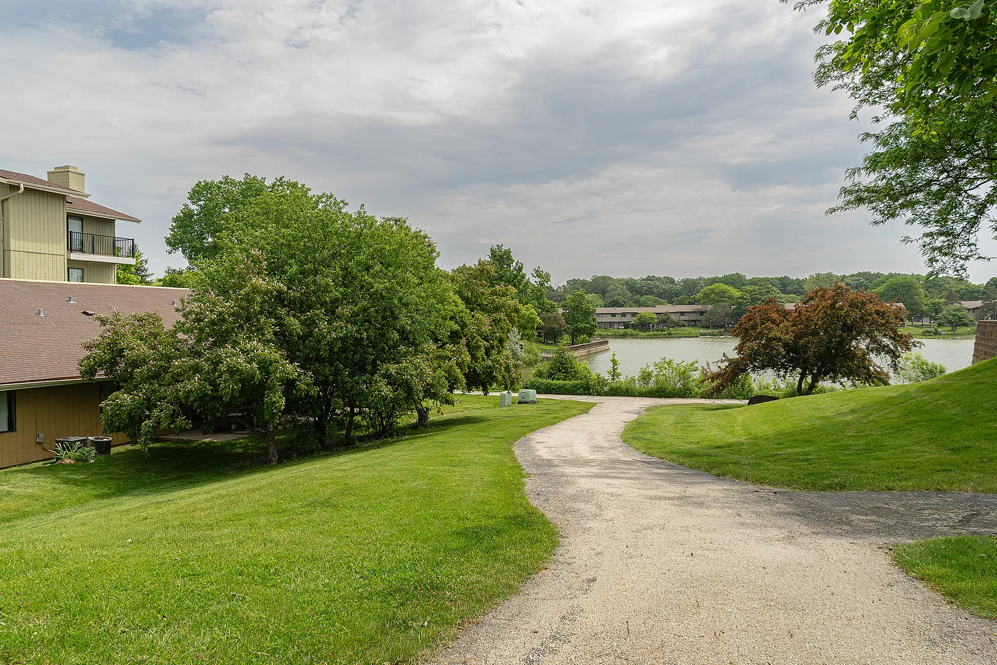 Scenic apartment complex with lush greenery and a serene lake view, offering a peaceful natural retreat.
