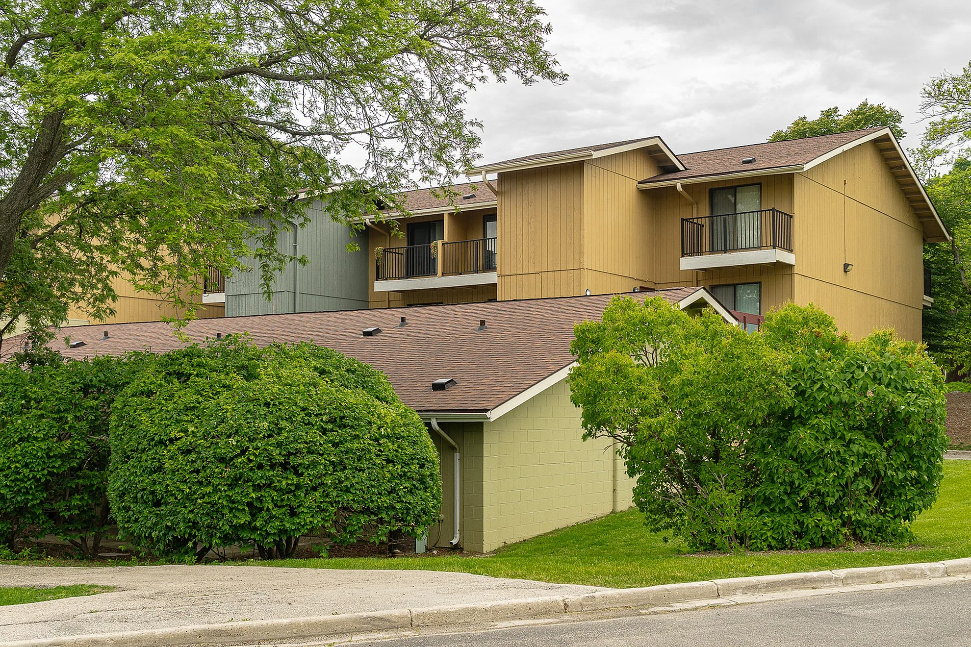 Charming apartment complex with lush greenery and modern balconies, offering a serene and picturesque living environment.