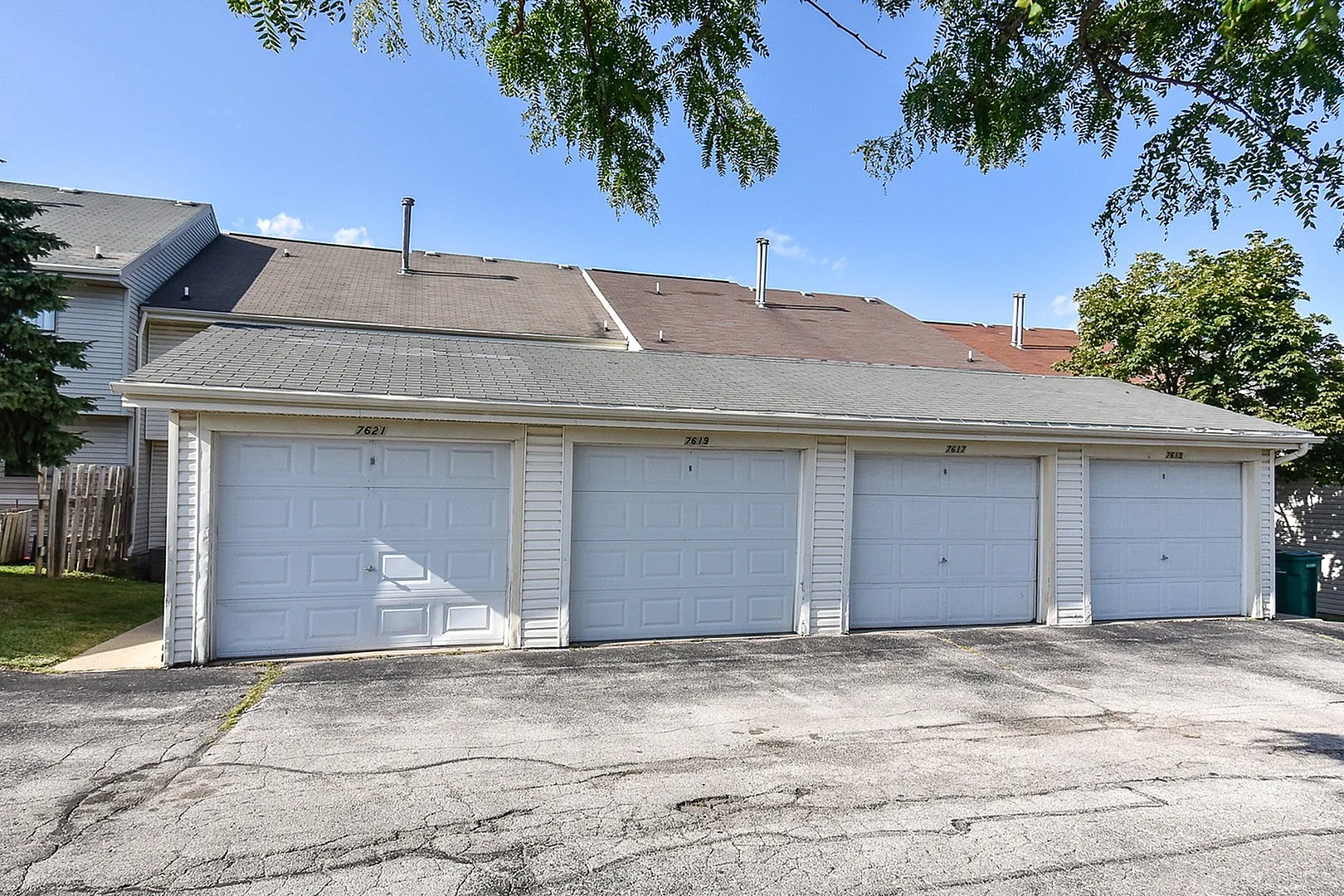 Inviting row of spacious garages with modern doors, set against a clear blue sky and vibrant greenery.