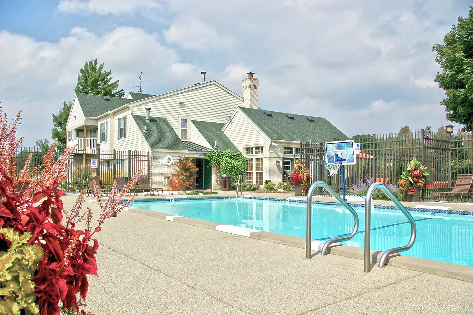 Charming apartment complex with a pristine swimming pool, lush landscaping, and cozy outdoor seating.