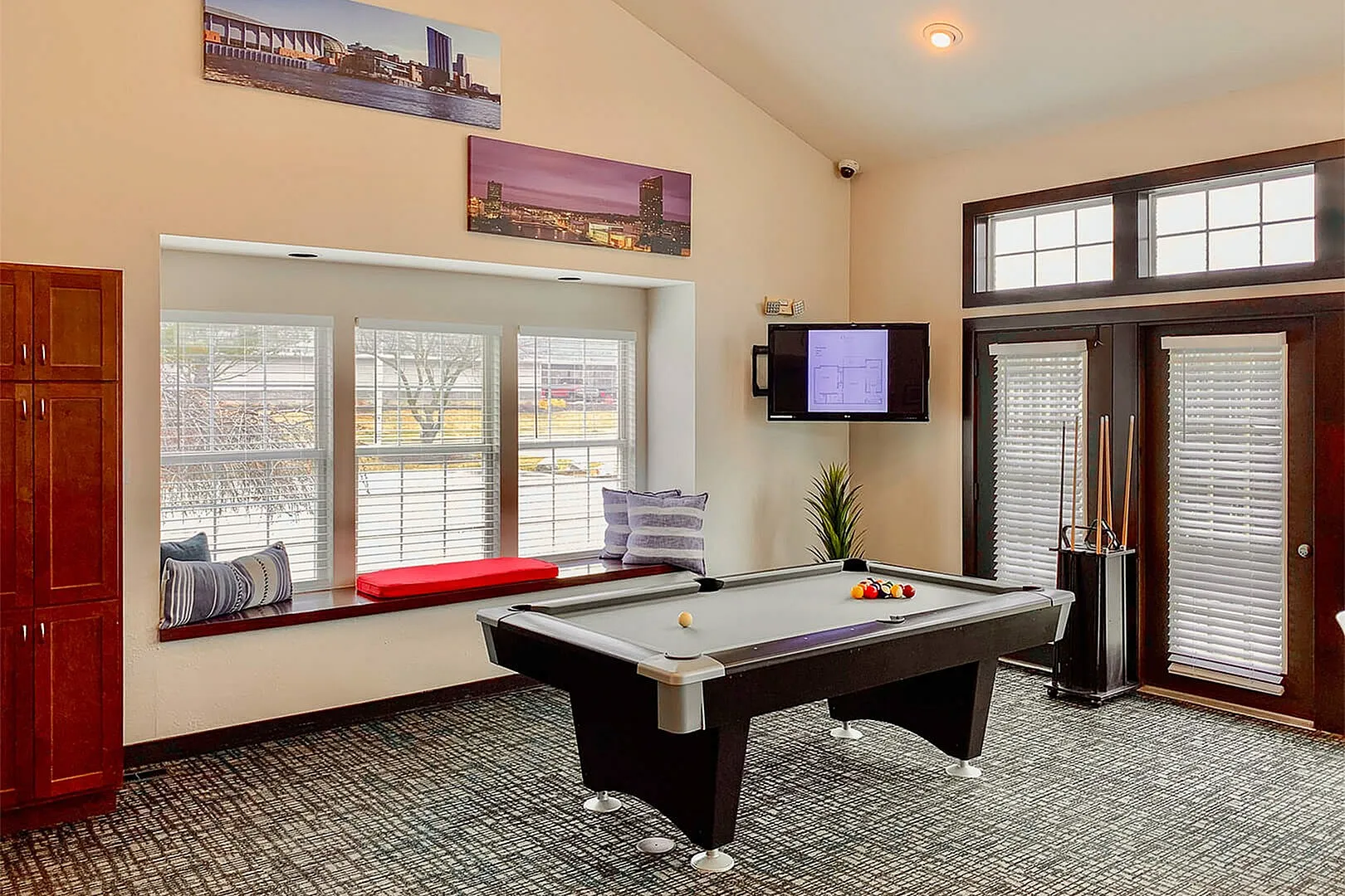 Elegant entertainment room with a modern pool table, cozy window seating, and stylish decor. Ideal for social gatherings.