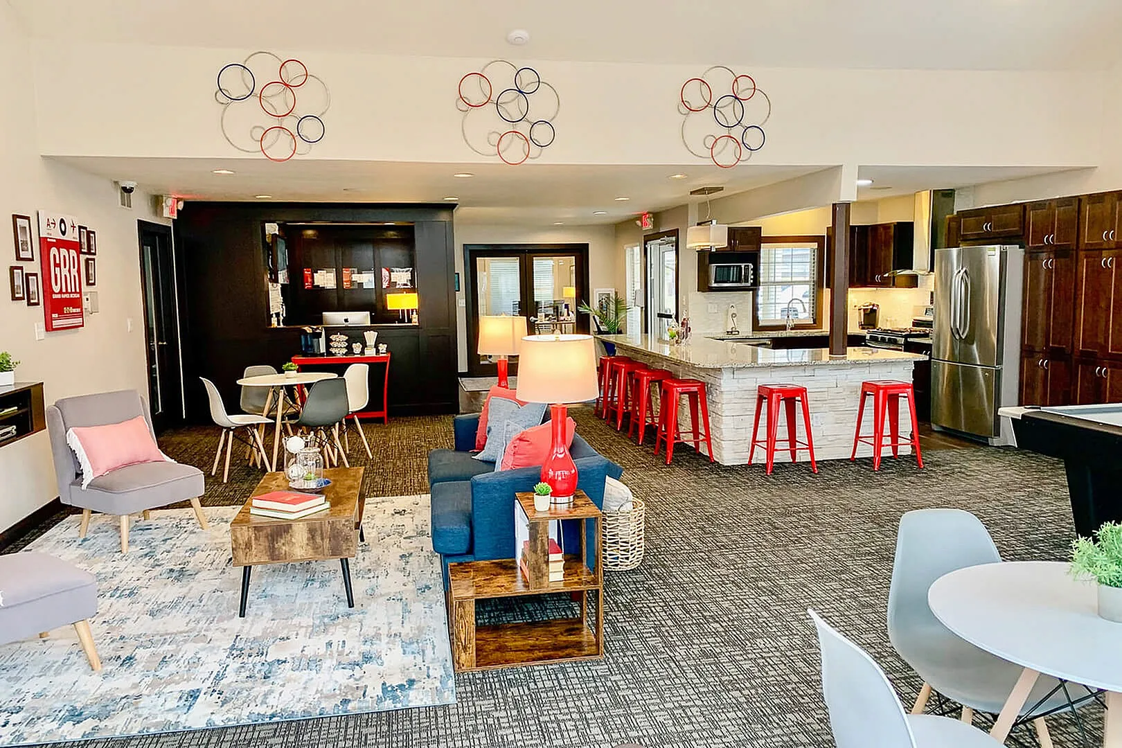 Inviting open-concept living area featuring a stylish seating arrangement, vibrant decor, and a modern kitchen with bar seating.