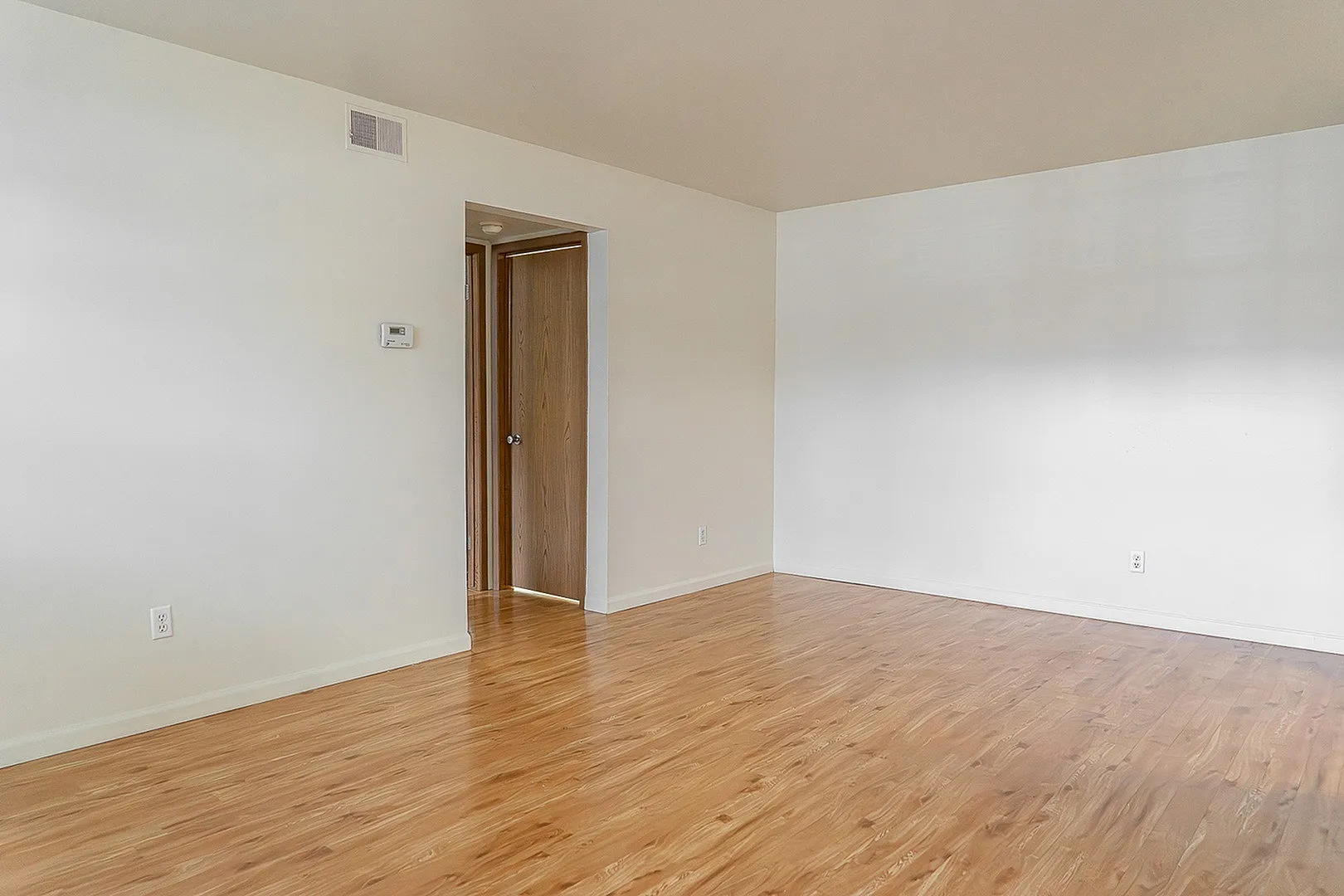 Bright, inviting room with sleek wooden flooring and a minimalist design, perfect for modern living.