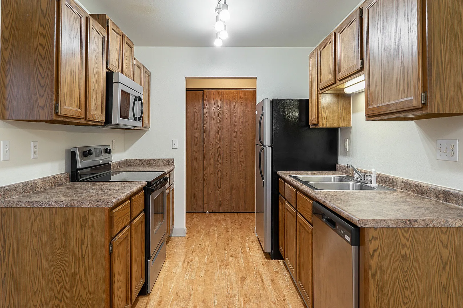 Modern galley kitchen with sleek stainless steel appliances, abundant wooden cabinetry, and elegant countertops.