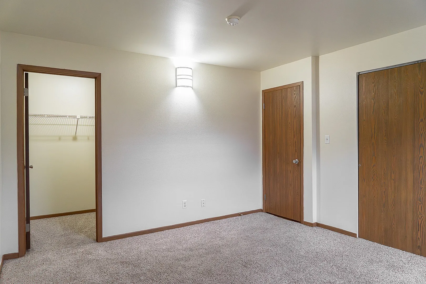 Elegant and spacious bedroom with plush carpet, featuring a well-designed walk-in closet for ample storage.
