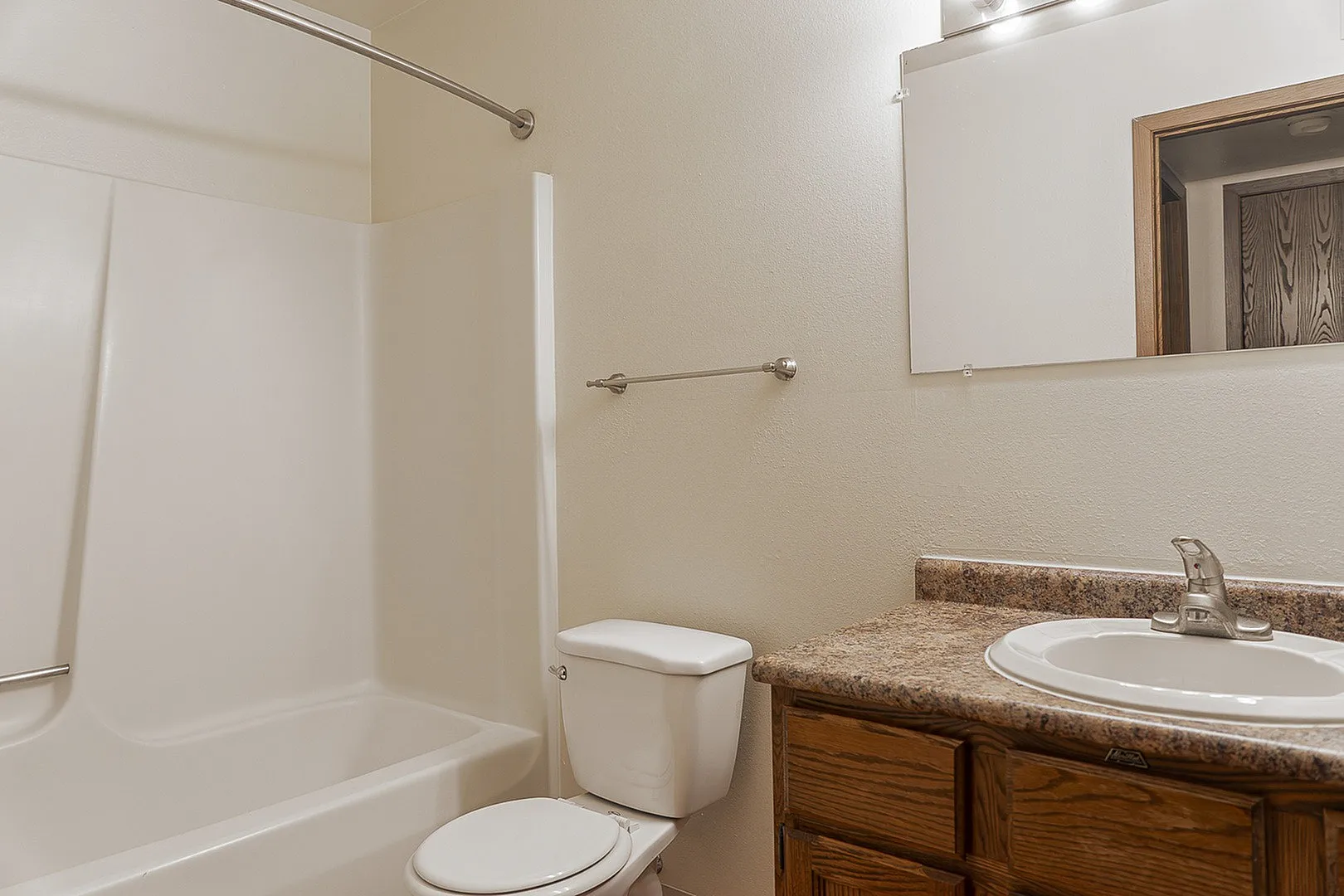 Bright and modern bathroom featuring a tub-shower combo, elegant sink with granite countertop, and ample storage cabinet.