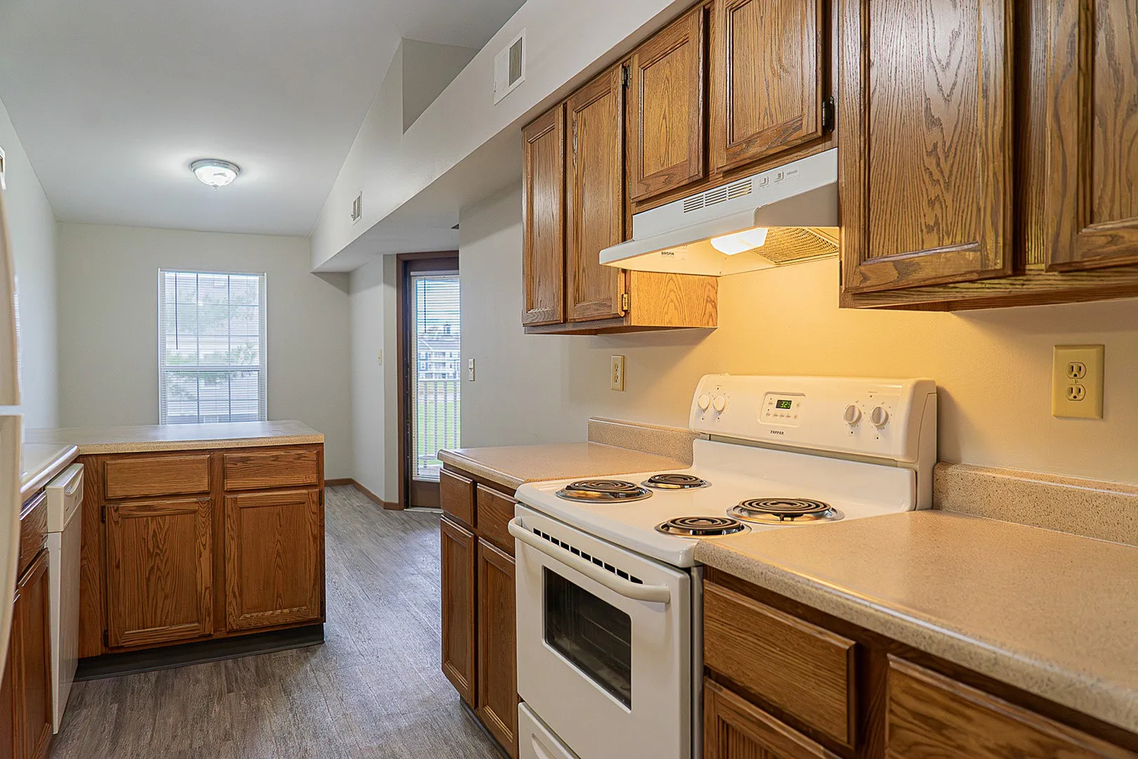 Inviting kitchen with warm wooden cabinetry, sleek countertops, and ample natural light from large windows.