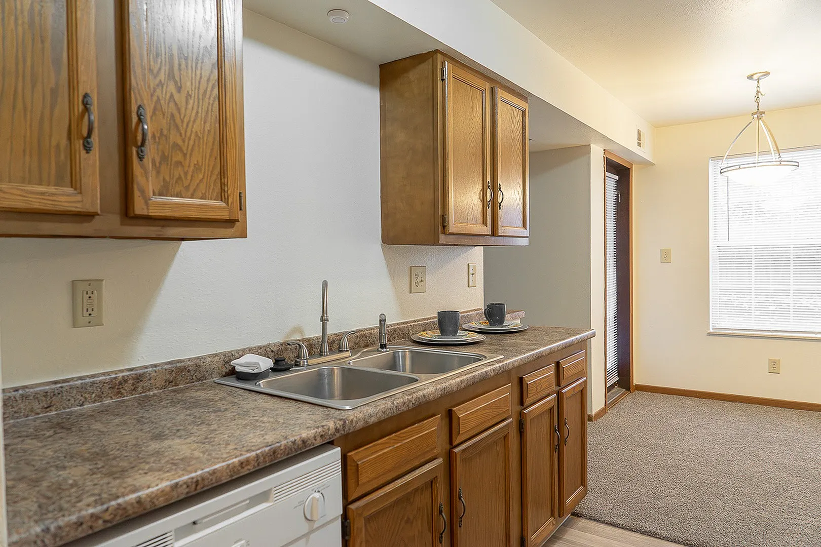Charming kitchen with warm wooden cabinetry, modern fixtures, and a cozy dining nook, bathed in natural light.