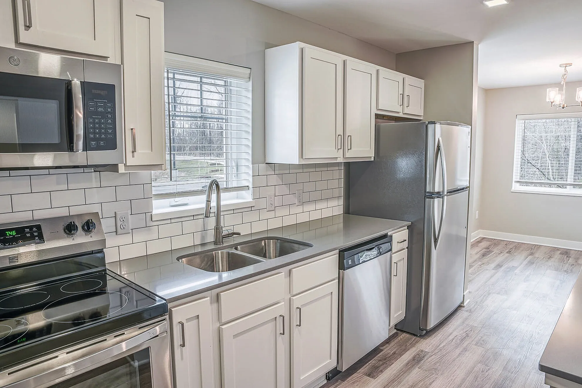 Bright modern kitchen with sleek stainless steel appliances, white cabinetry, and elegant tile backsplash.