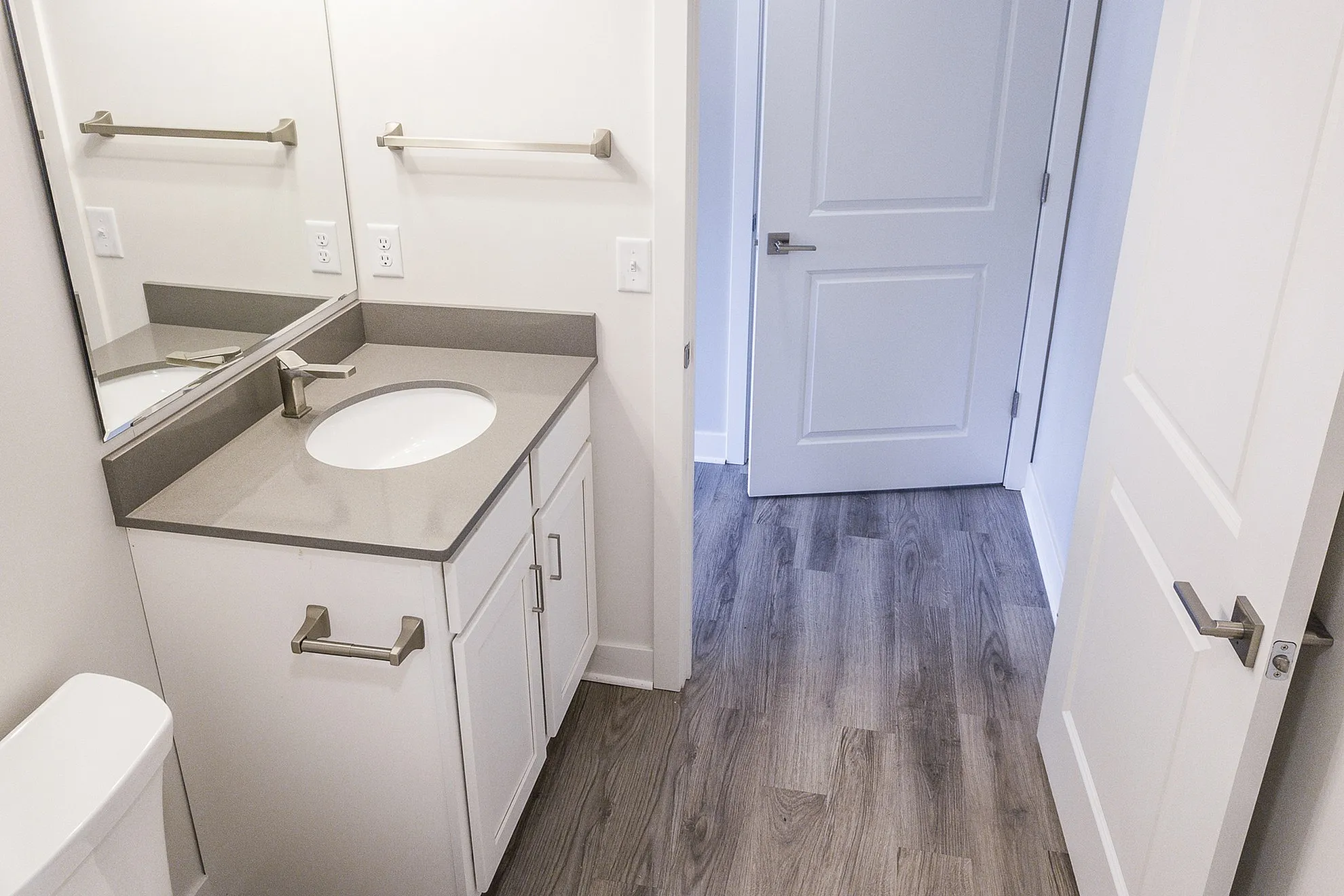 Elegant bathroom with modern fixtures, a sleek countertop, and stylish hardwood flooring.