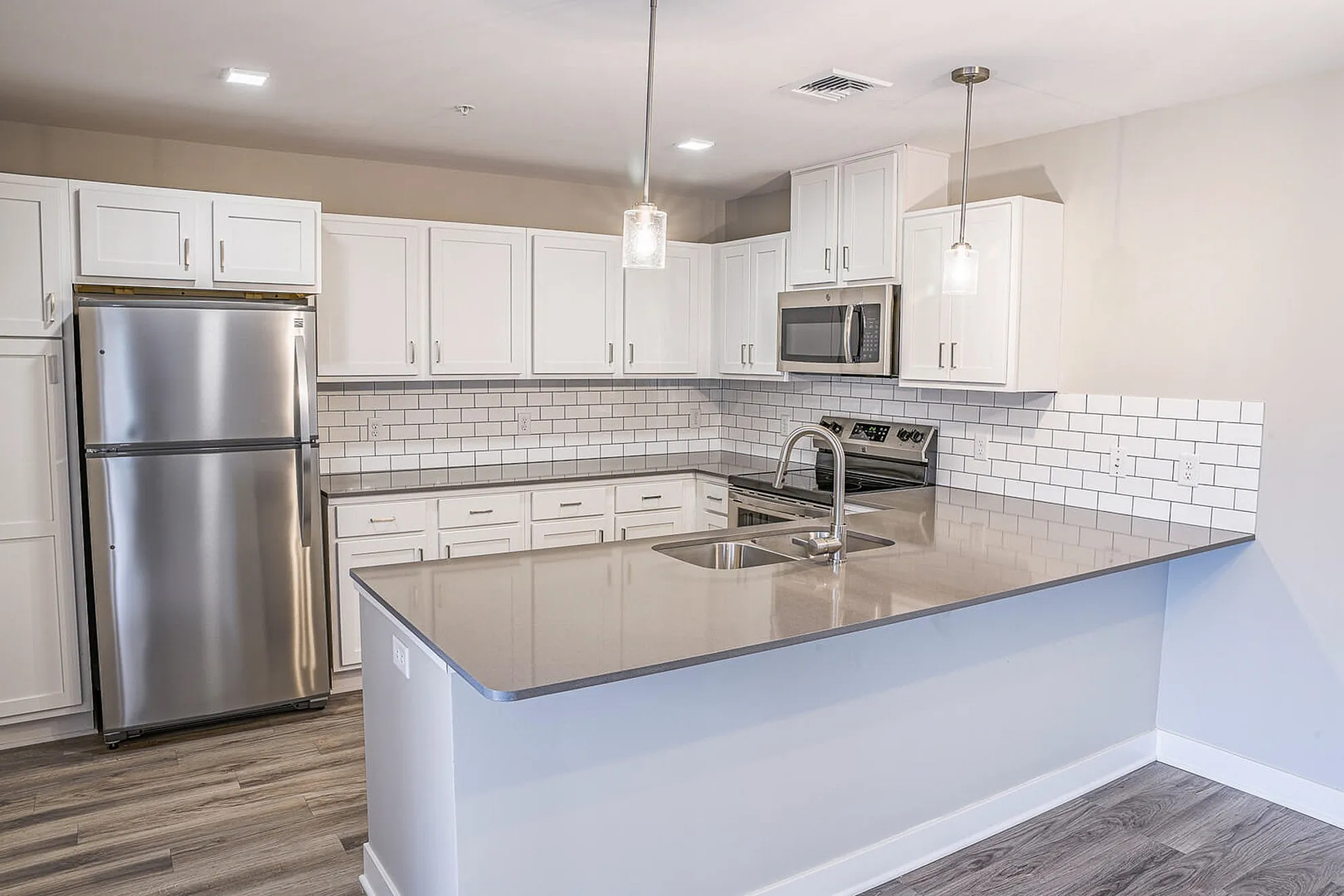 Modern kitchen featuring sleek stainless steel appliances, elegant white cabinetry, and a spacious subway tile backsplash.