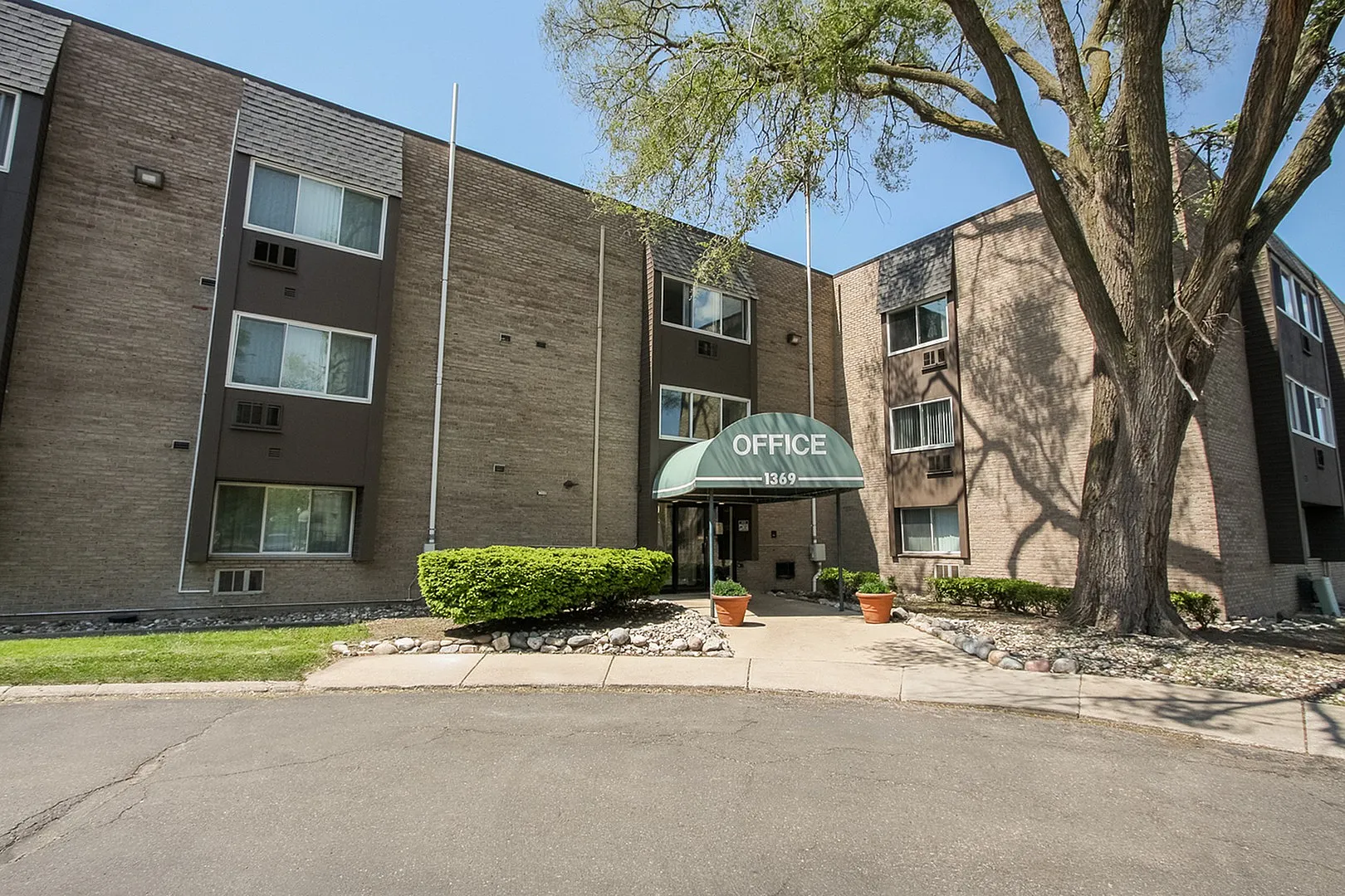 Inviting apartment complex exterior featuring a welcoming office entrance with greenery and modern architecture.