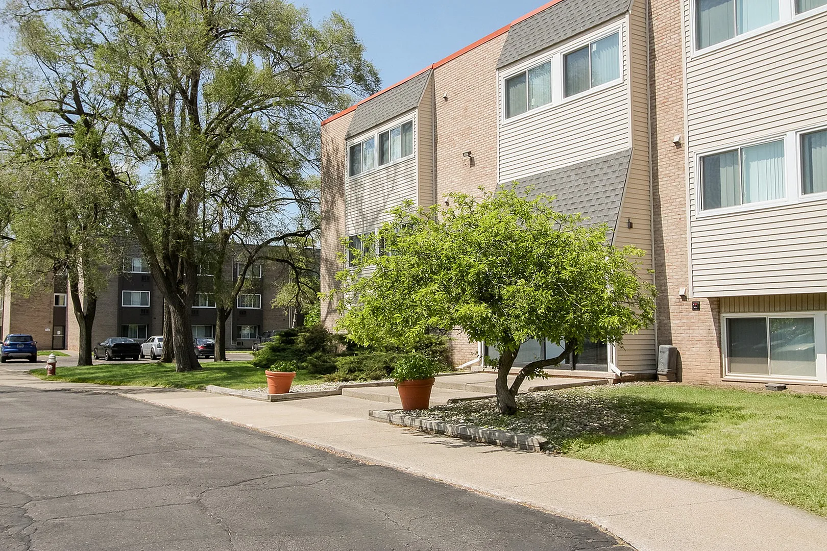 Charming apartment complex surrounded by lush greenery and mature trees, offering a peaceful living environment.