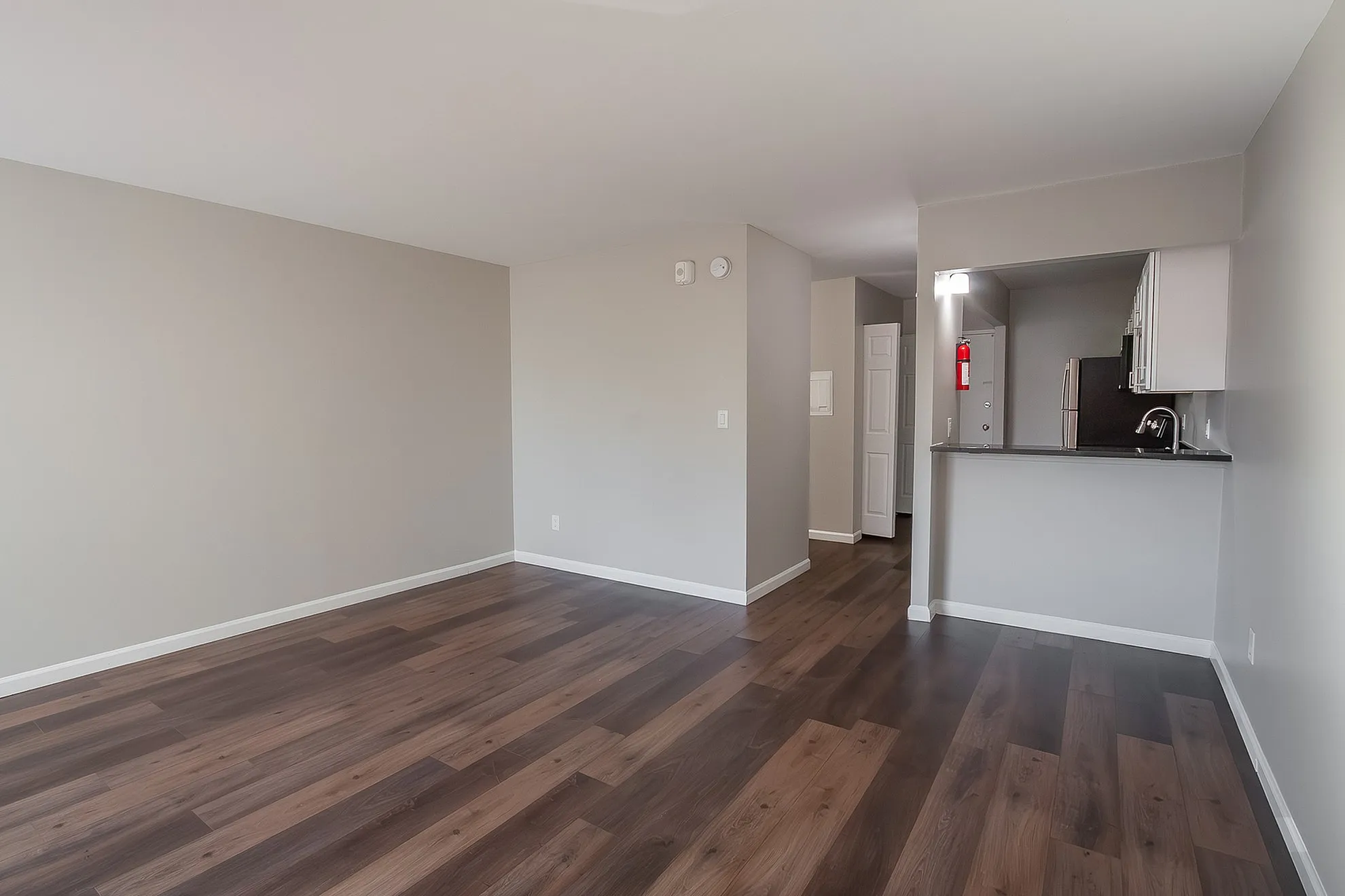 Modern apartment featuring elegant hardwood floors, neutral walls, and an open-concept layout with a kitchenette, ideal for stylish living.