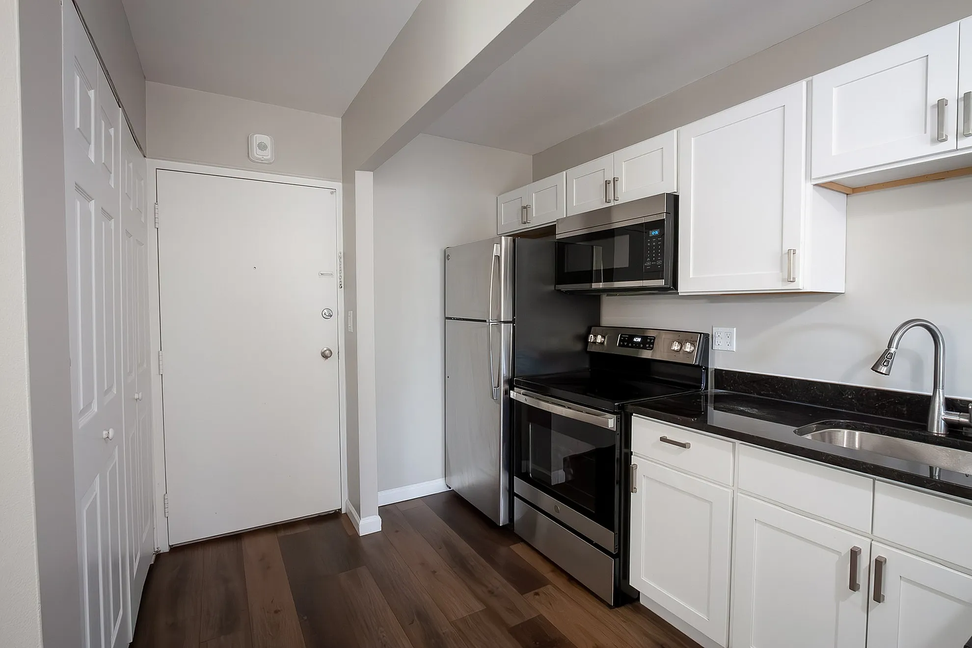 Modern kitchen with sleek stainless steel appliances, elegant white cabinetry, and rich wood flooring for a stylish touch.